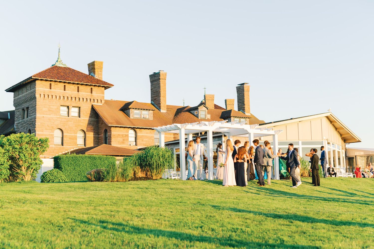 Panoramic view of a rustic barn-style event venue nestled on a rolling green hillside at sunset.