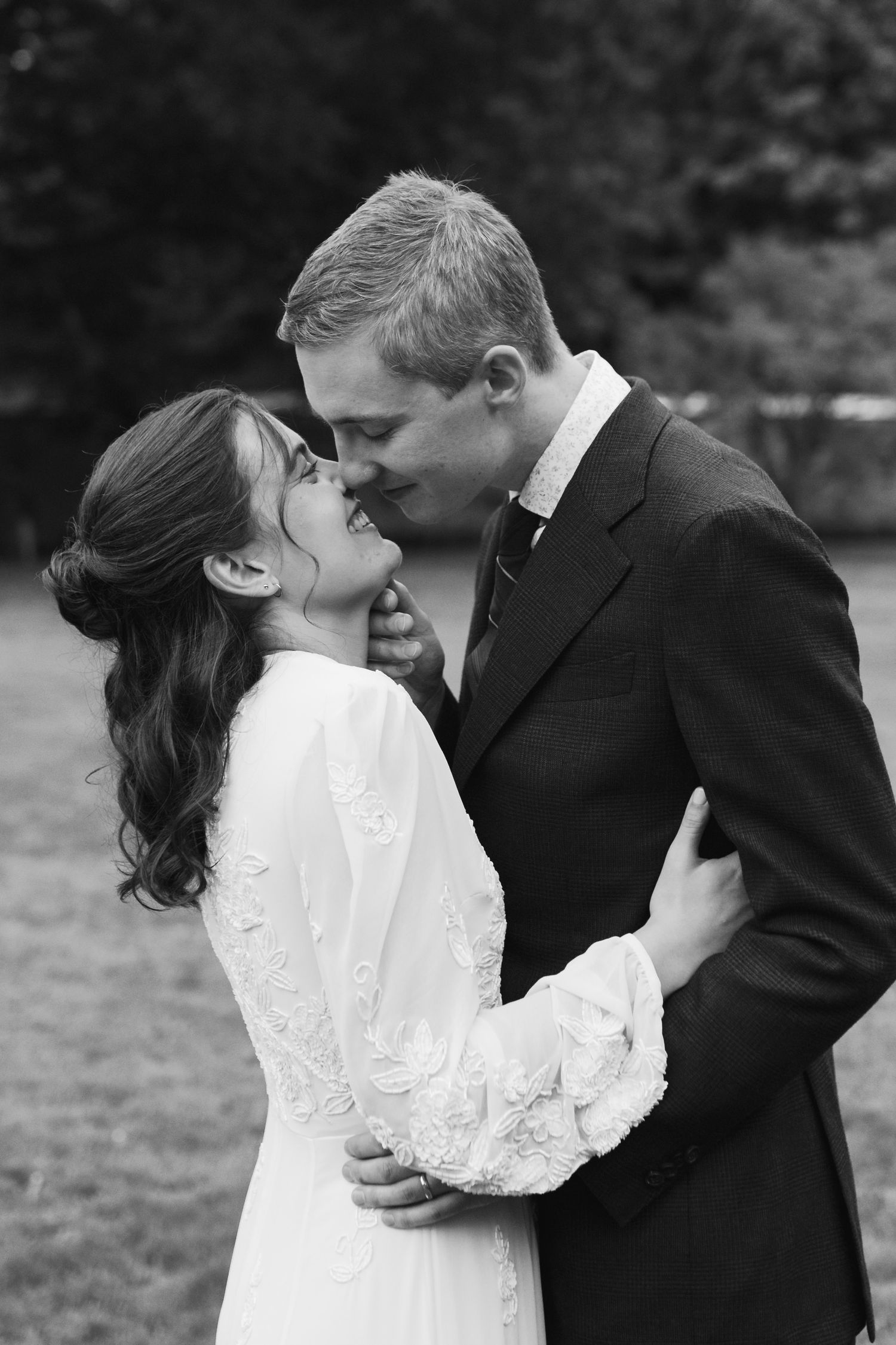 A romantic series of black and white wedding photos showing a couple embracing and kissing in an outdoor setting.