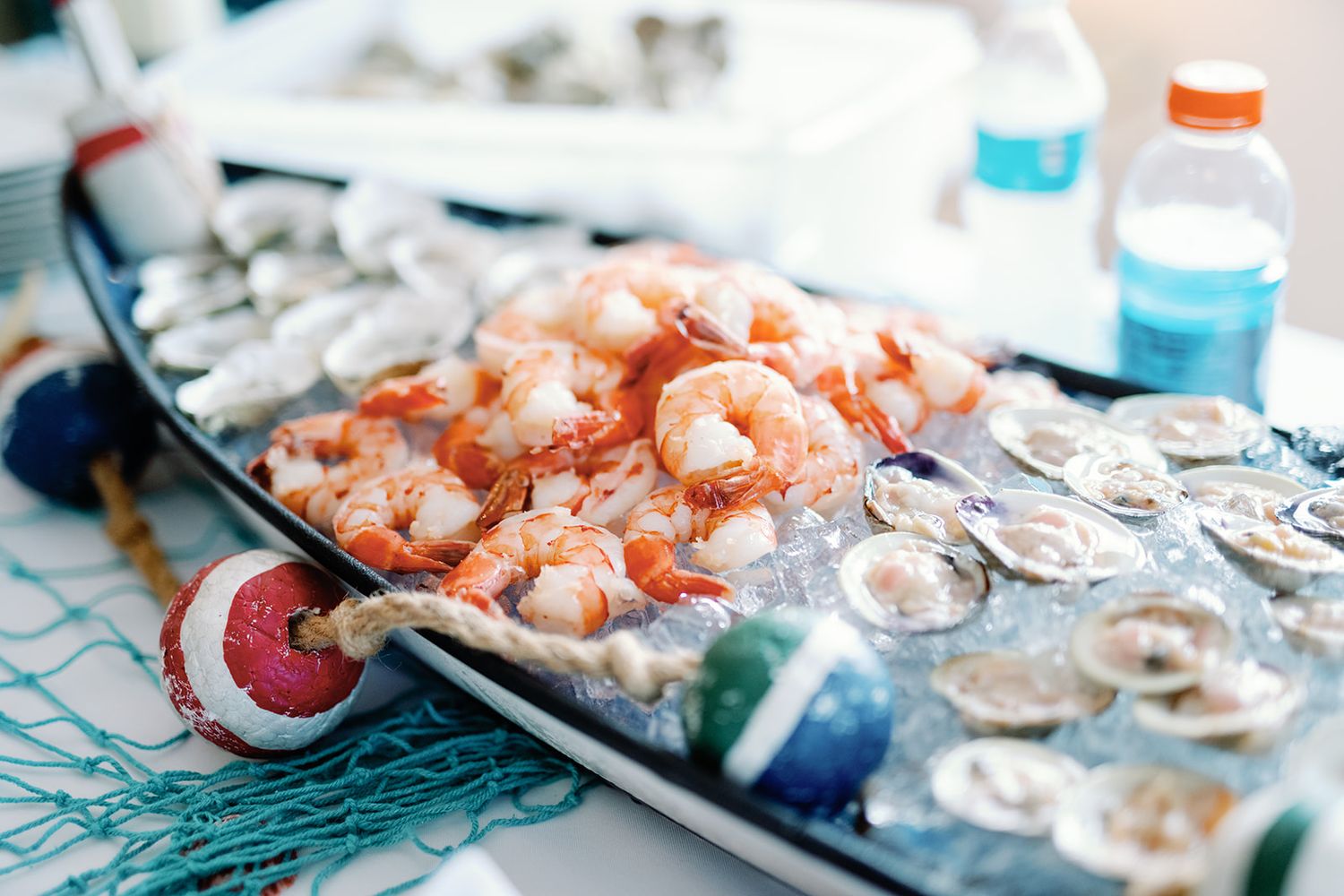 Fresh cooked shrimp and raw oysters on ice displayed on a serving platter at a seafood feast.