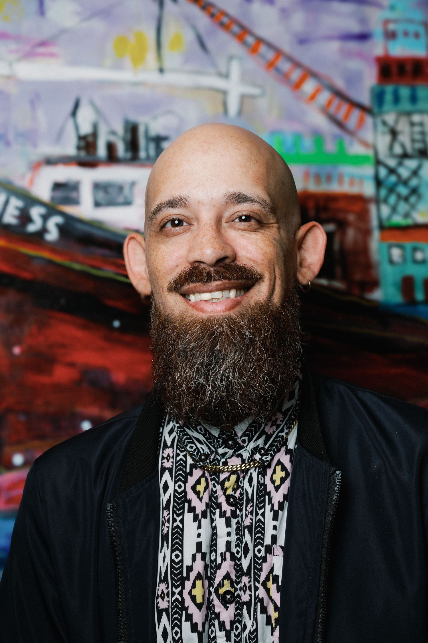 Sequence of four headshots showing a bearded person in black clothing against colorful graffiti wall background.