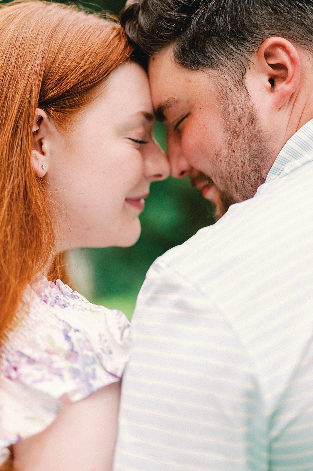 A romantic couple in white outfits share intimate close moments in a sun-dappled outdoor setting.