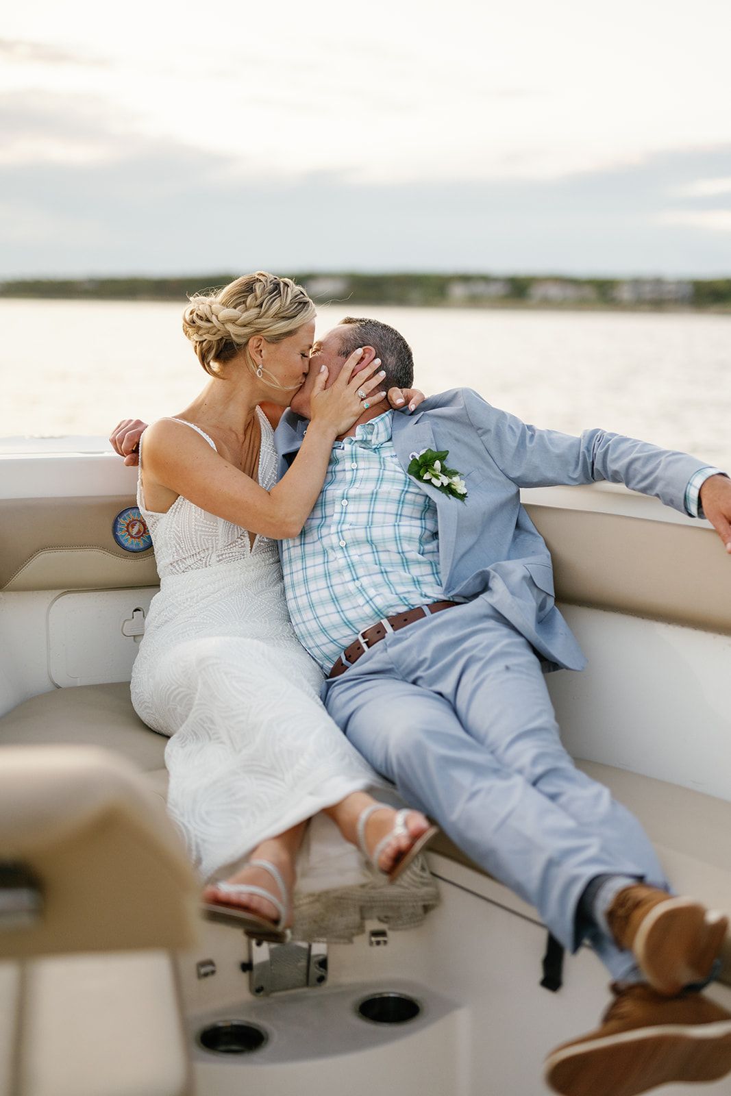 A couple shares a romantic moment on a boat deck with water and shoreline visible in the background.