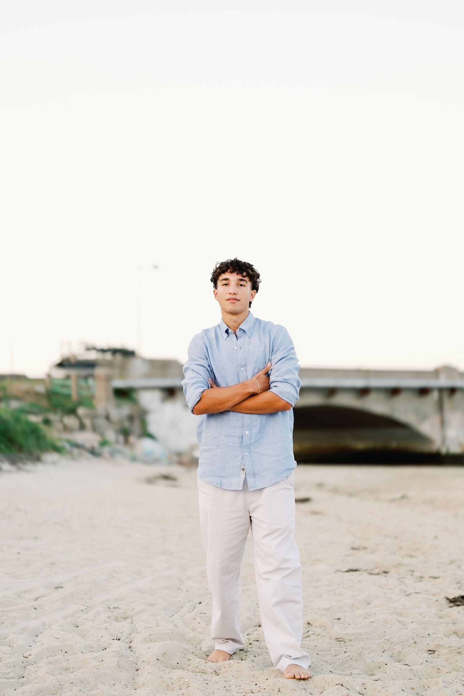 A series of beach portraits showing a person in a light blue shirt and white pants standing on sandy shores at sunset.