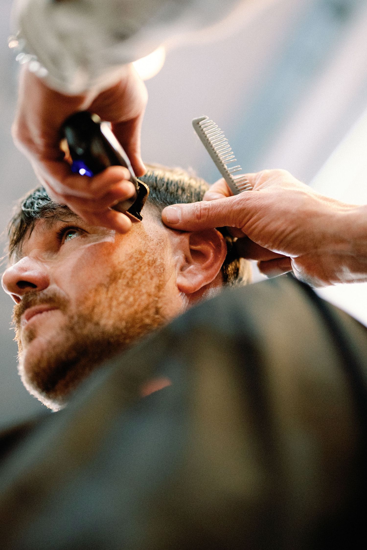 Professional barber uses clippers and comb to give a precise haircut in a modern barbershop setting.