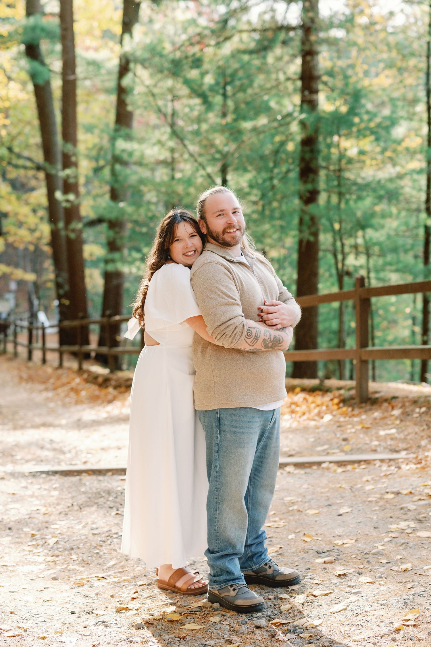 A heartwarming outdoor photo series showing a tender embrace between two people on a wooded autumn trail.