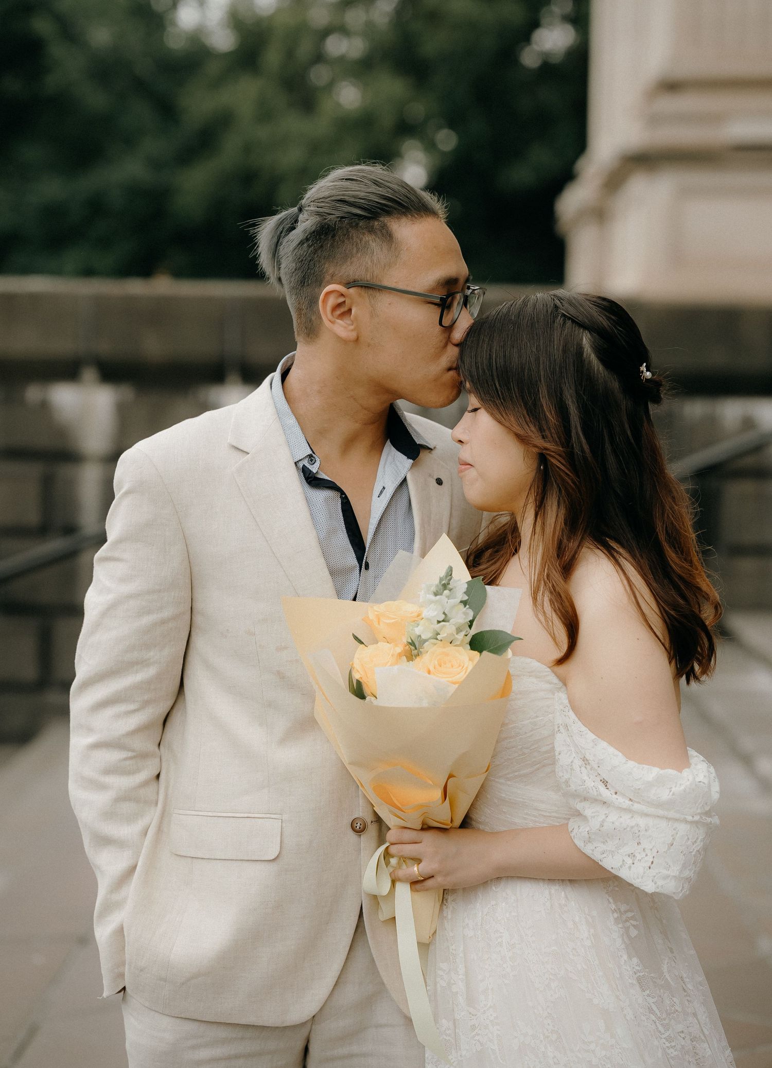A romantic couple in wedding attire shares tender moments while holding a glowing bouquet of flowers.