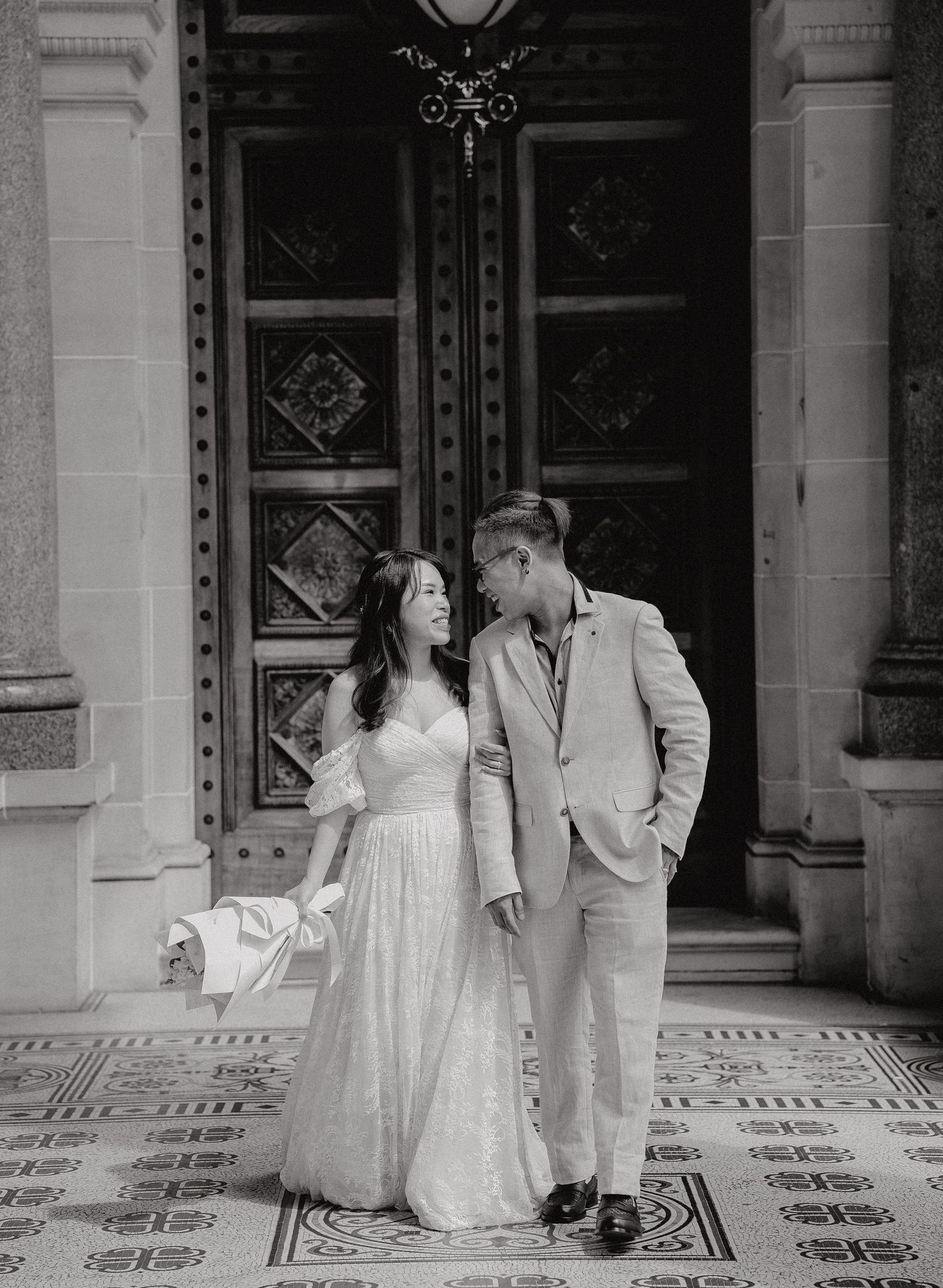 A romantic wedding couple shares intimate moments in a series of black and white photographs on an ornate tiled floor.