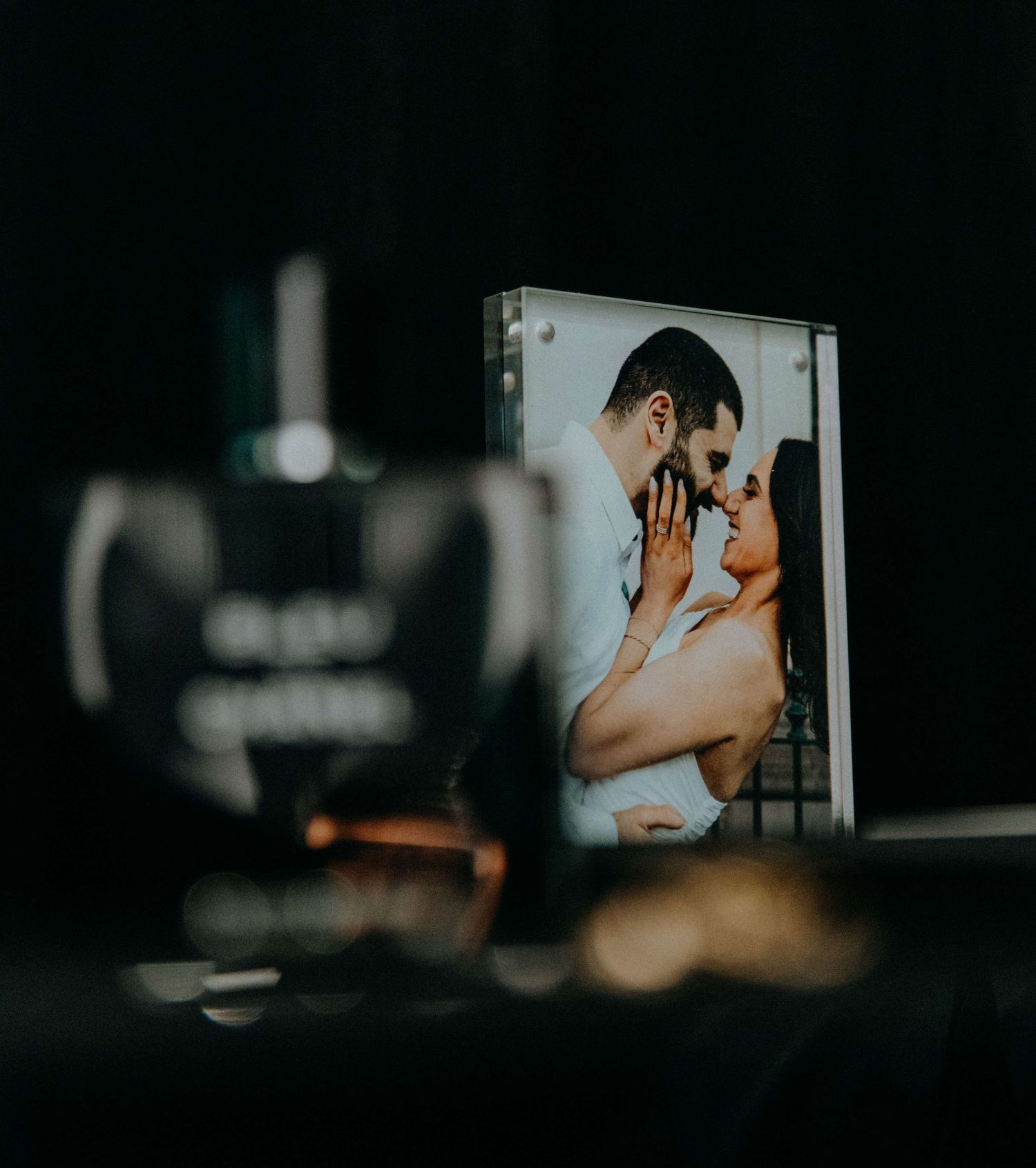 A romantic photograph displayed on screen behind out-of-focus camera equipment in a dark setting.