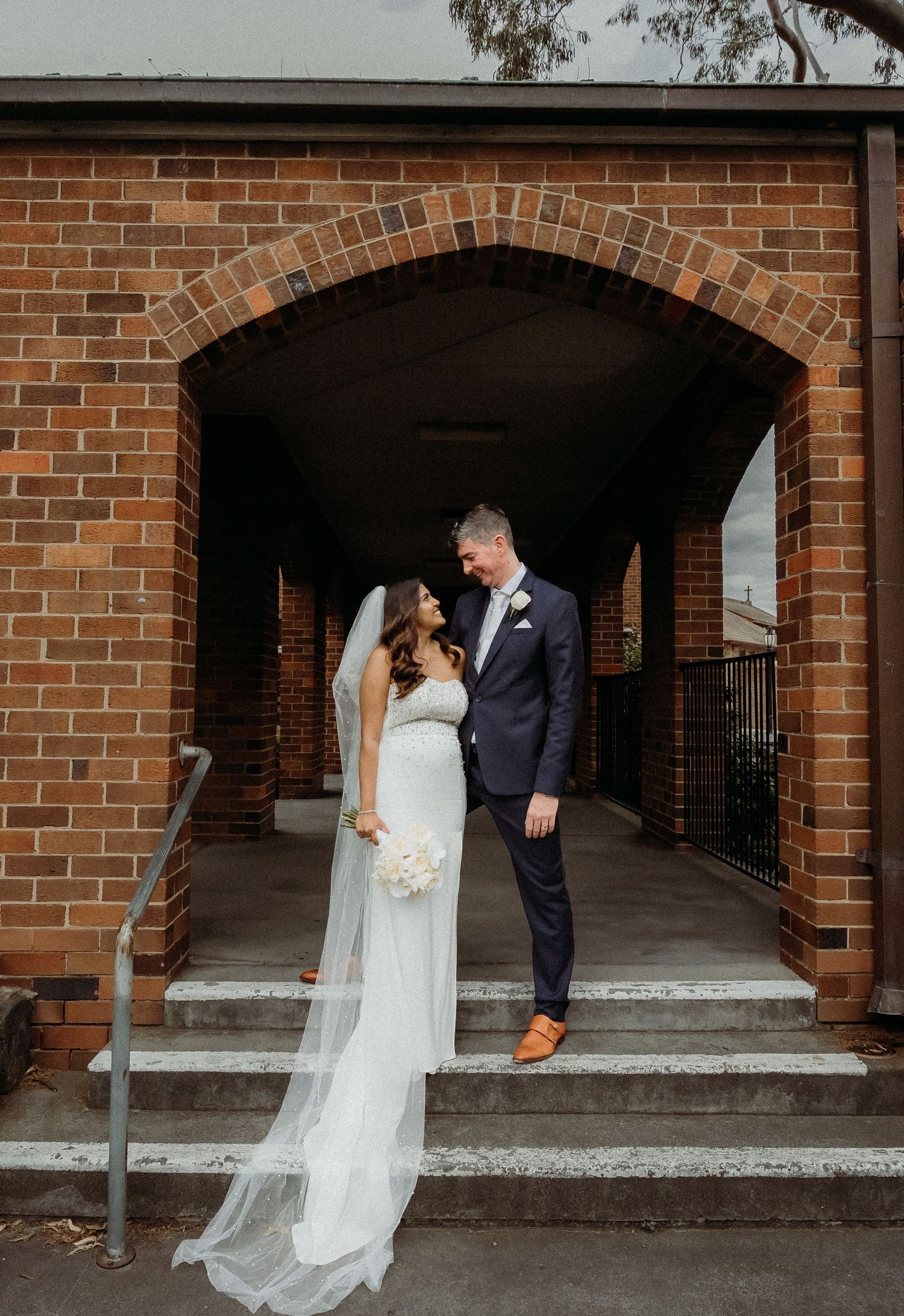 A bride and groom share romantic moments under brick archways in a series of candid wedding photos.