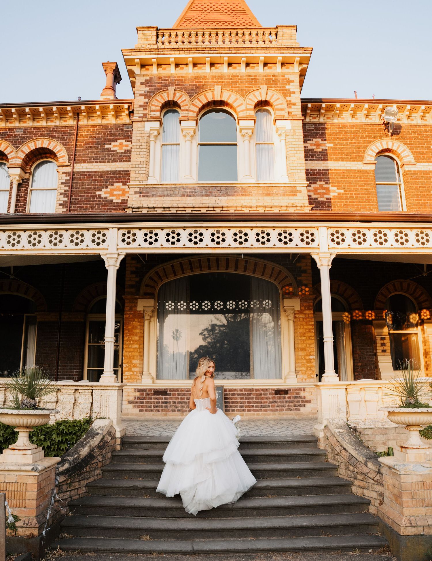 Historic brick mansion with ornate architectural details and white columns photographed at golden hour.