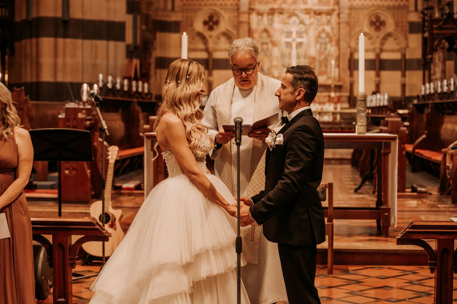 Couples dance on a hardwood floor during a romantic indoor wedding reception with warm lighting and elegant decor.
