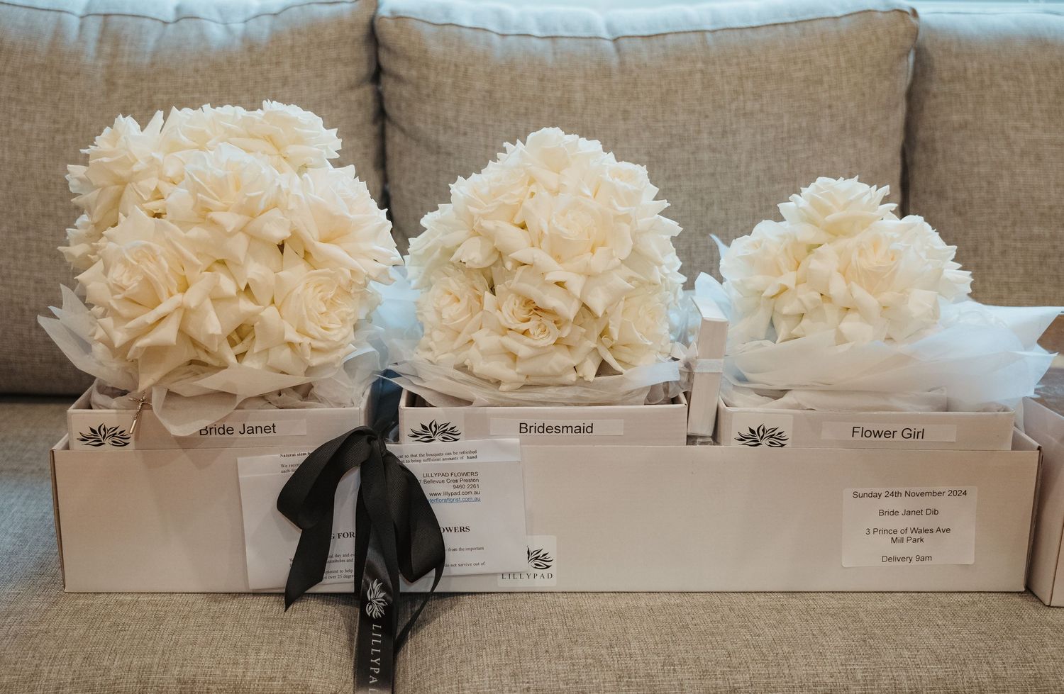 White floral tissue paper decorations arranged in a row along a beige wall create an elegant wedding reception backdrop.