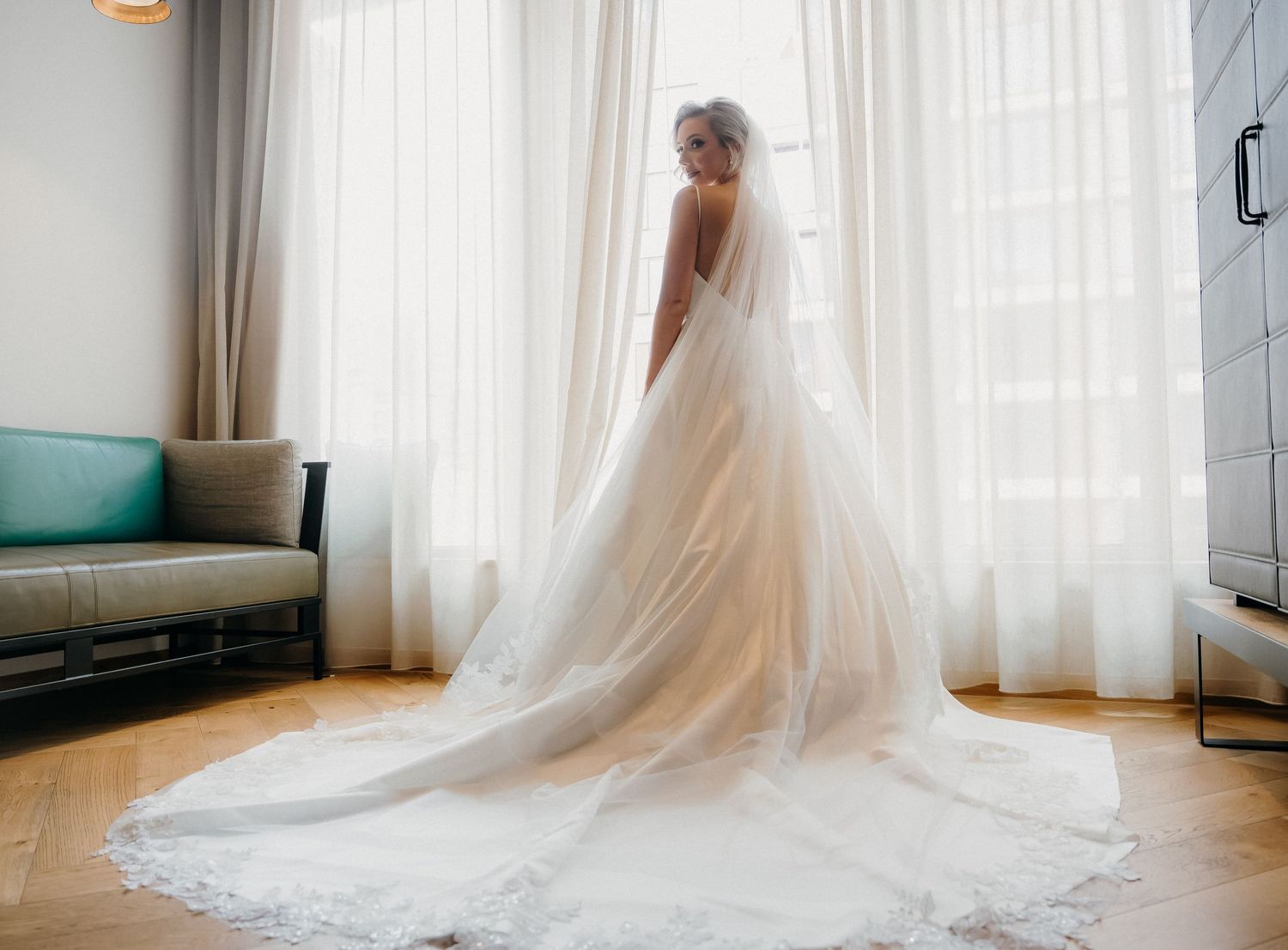 A flowing white wedding dress with a long train photographed in sequence across a bright sunlit room.
