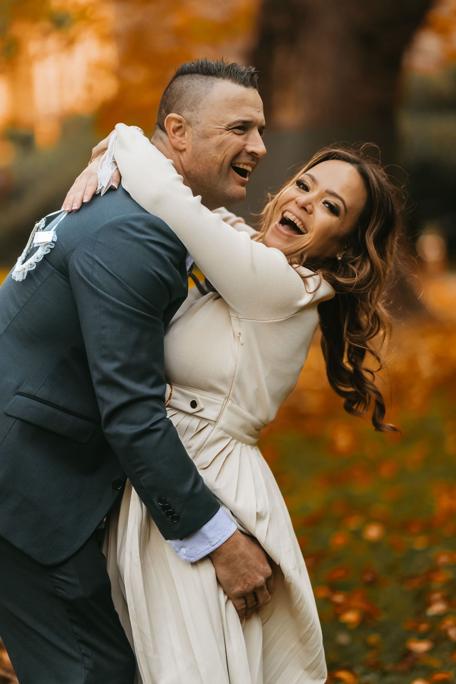 Joyful fall photo session showing a couple embracing and laughing together surrounded by autumn foliage.