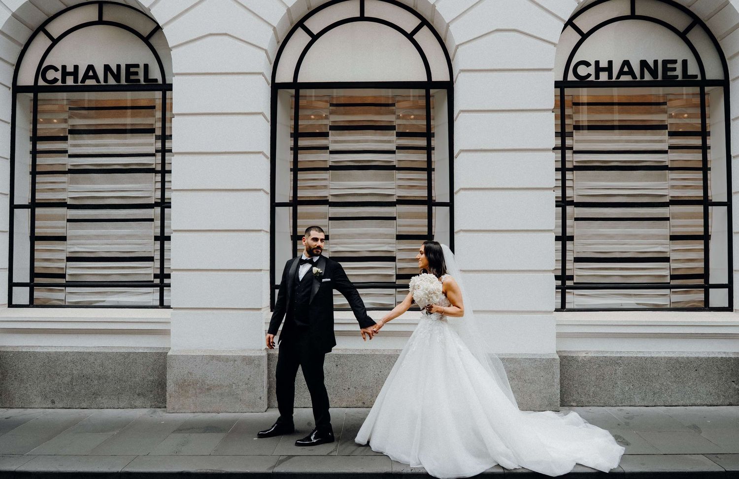 A series of black and white photos showing movement along a building facade with wedding attire and flowing white dress.