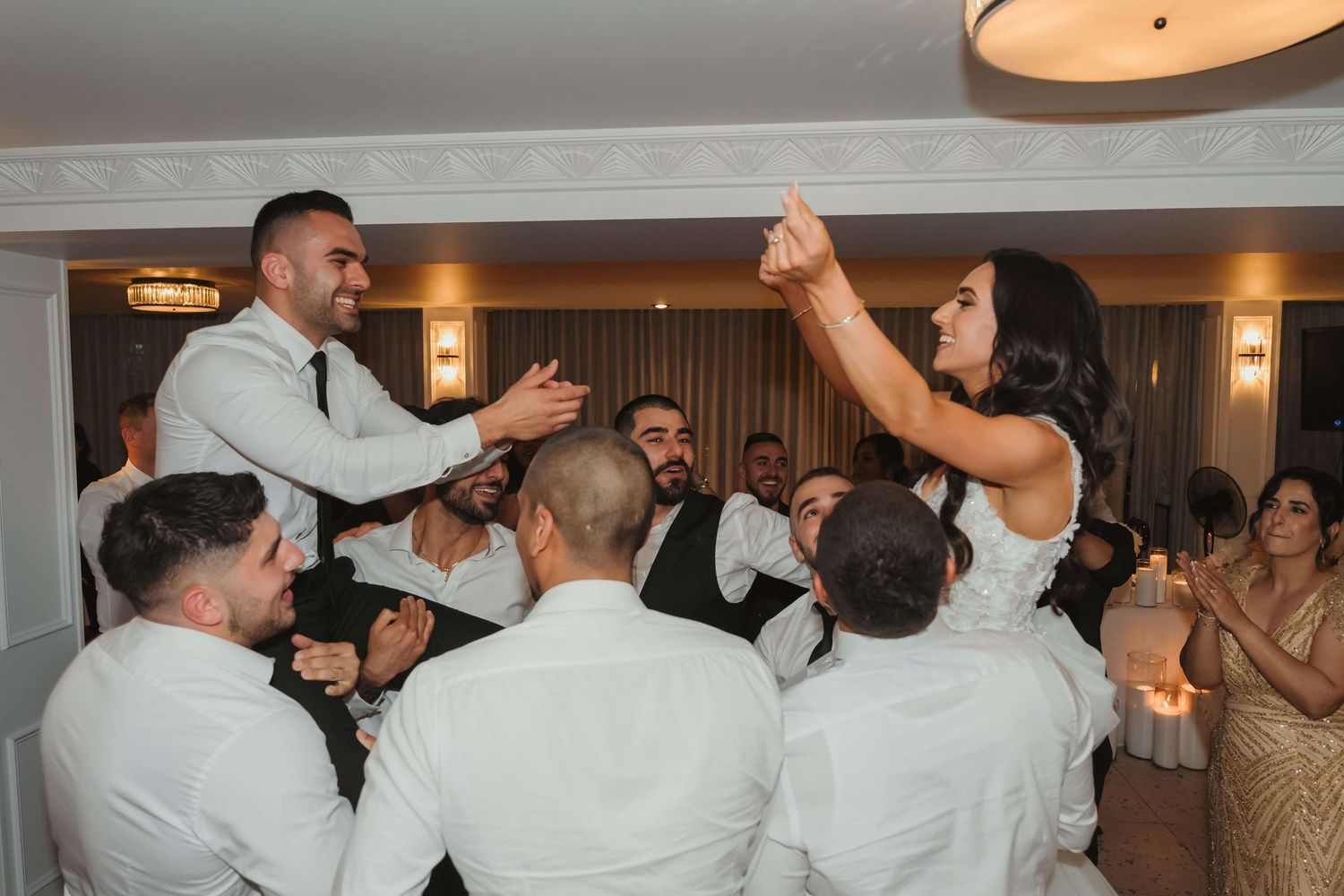 A wedding reception dance party with guests dancing and celebrating in a hotel ballroom.
