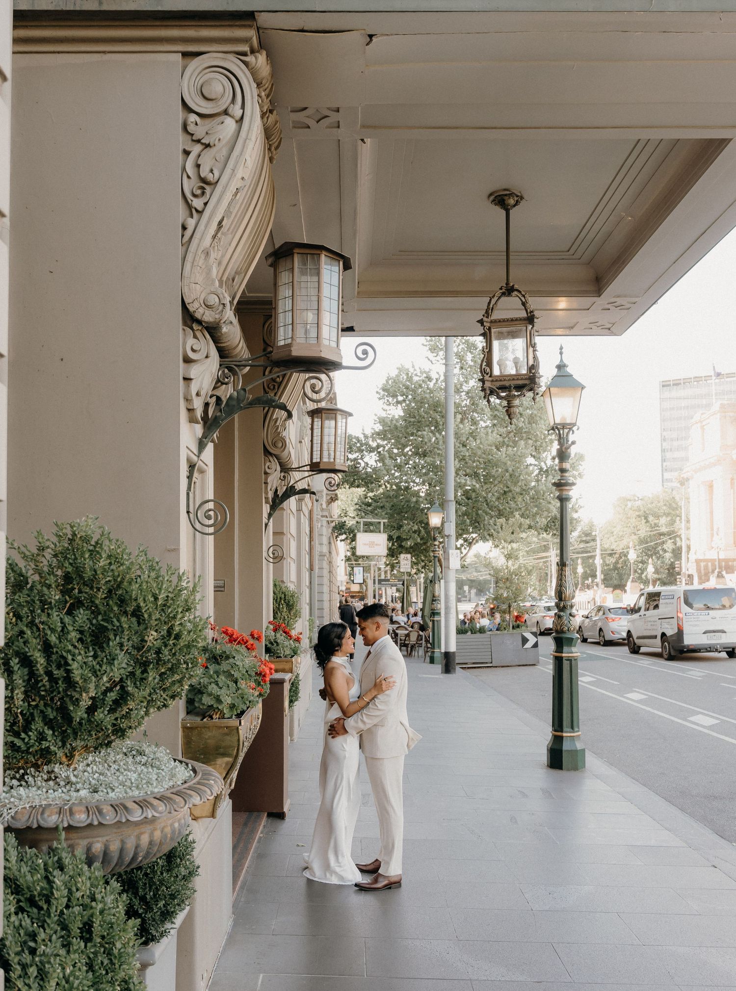 A covered walkway with ornate columns and lanterns leads along a historic building in New Orleans.