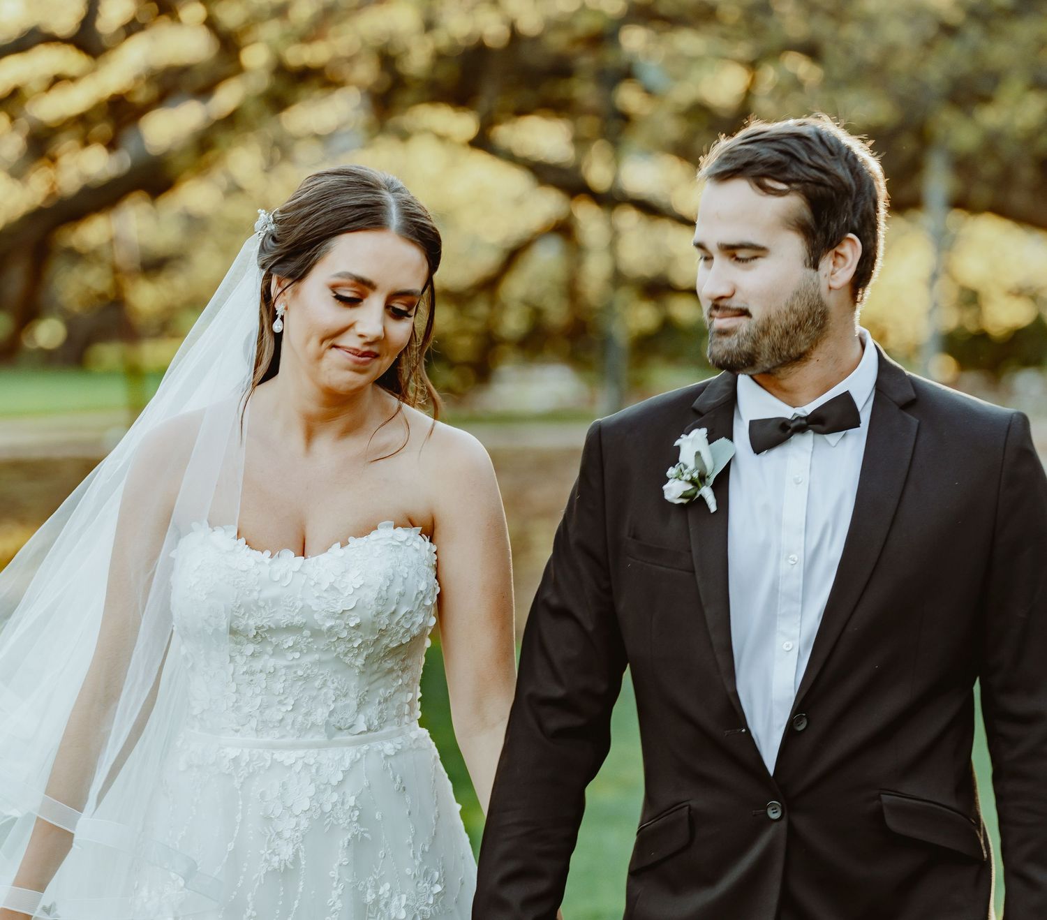 A joyful couple shares tender moments outdoors on their wedding day in elegant formal attire.