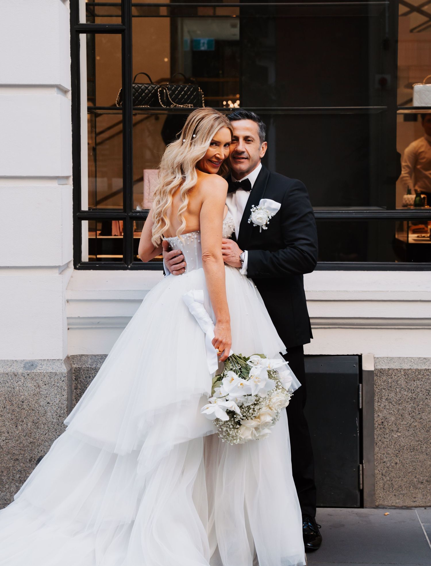 A romantic wedding moment captured in a series of black and white photos showing a couple embracing outside a building.
