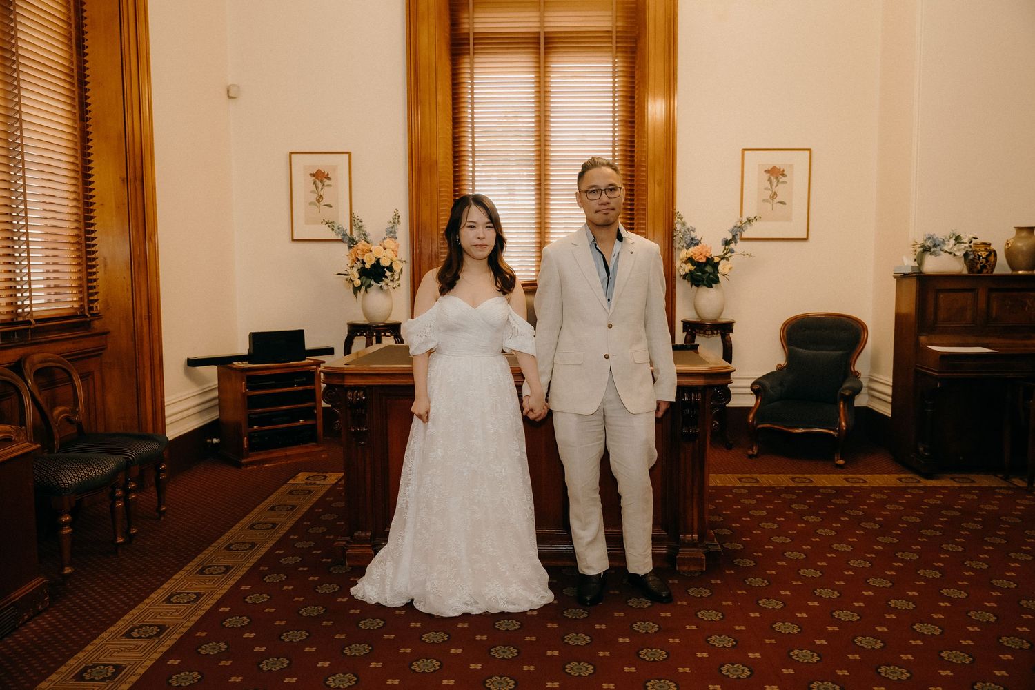 A couple poses together in an elegant room with wood trim and a patterned carpet for their wedding portrait.