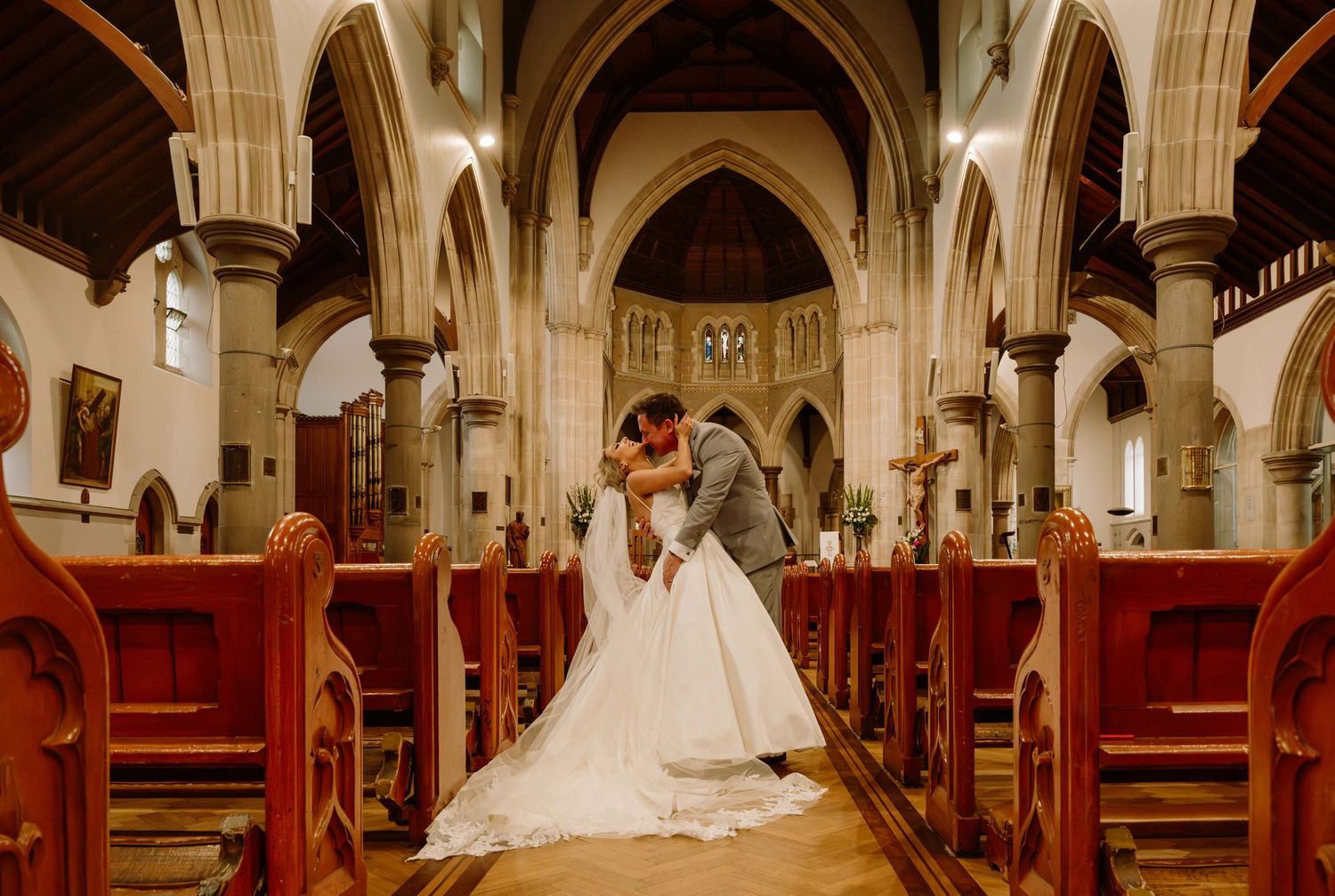 A bride and groom exchange vows during a traditional church wedding ceremony beneath ornate gothic arches.