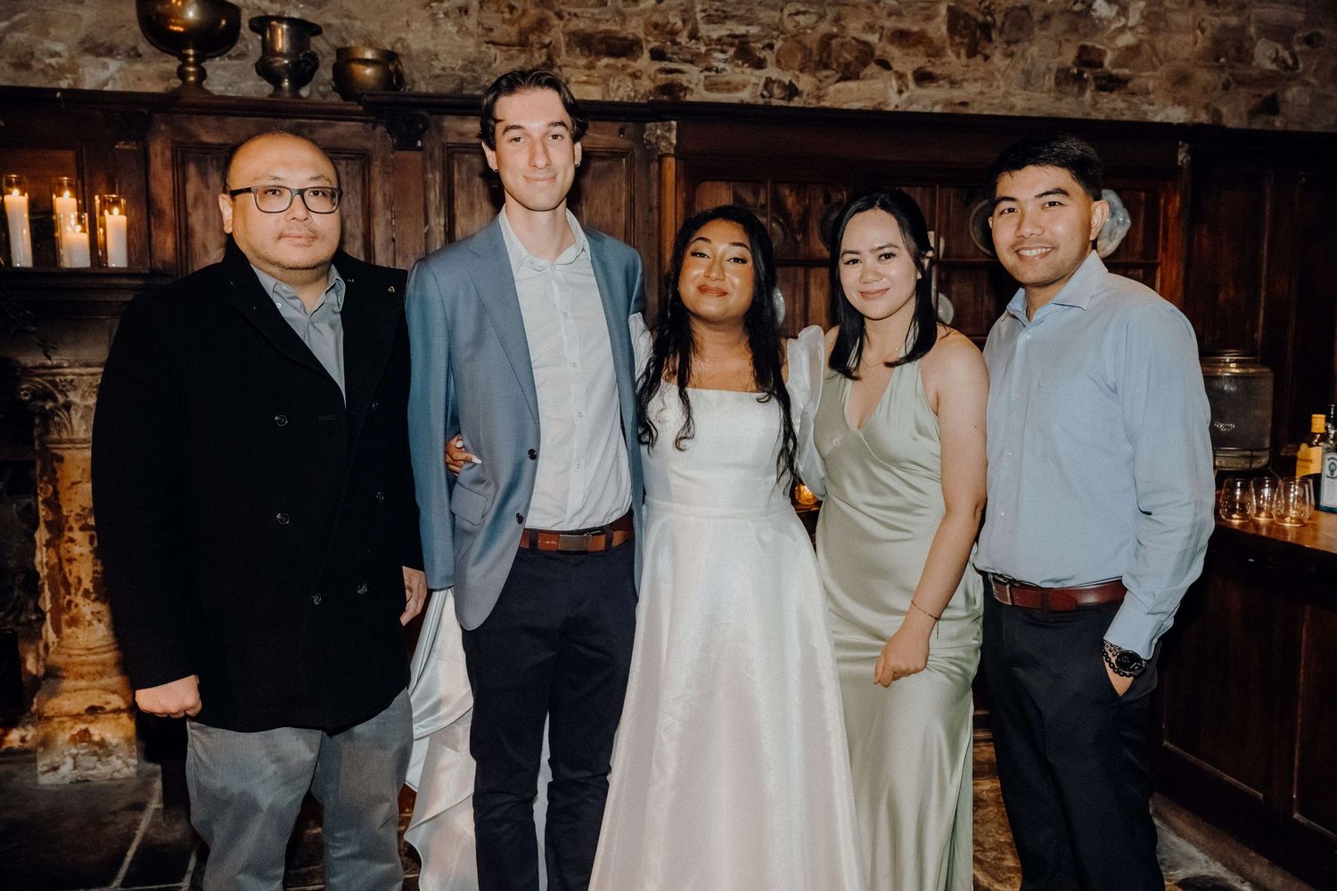 Guests celebrate at a dimly lit wedding reception in a rustic venue with exposed brick walls.