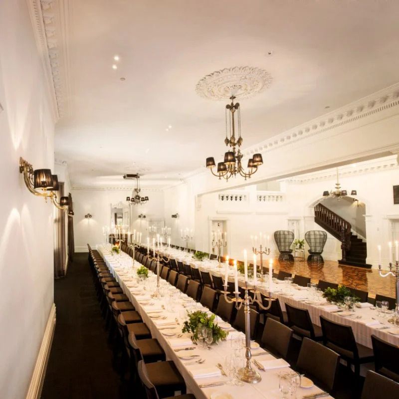 Elegant banquet hall with long white tables, chandeliers, and classic decor set for a formal dining event.