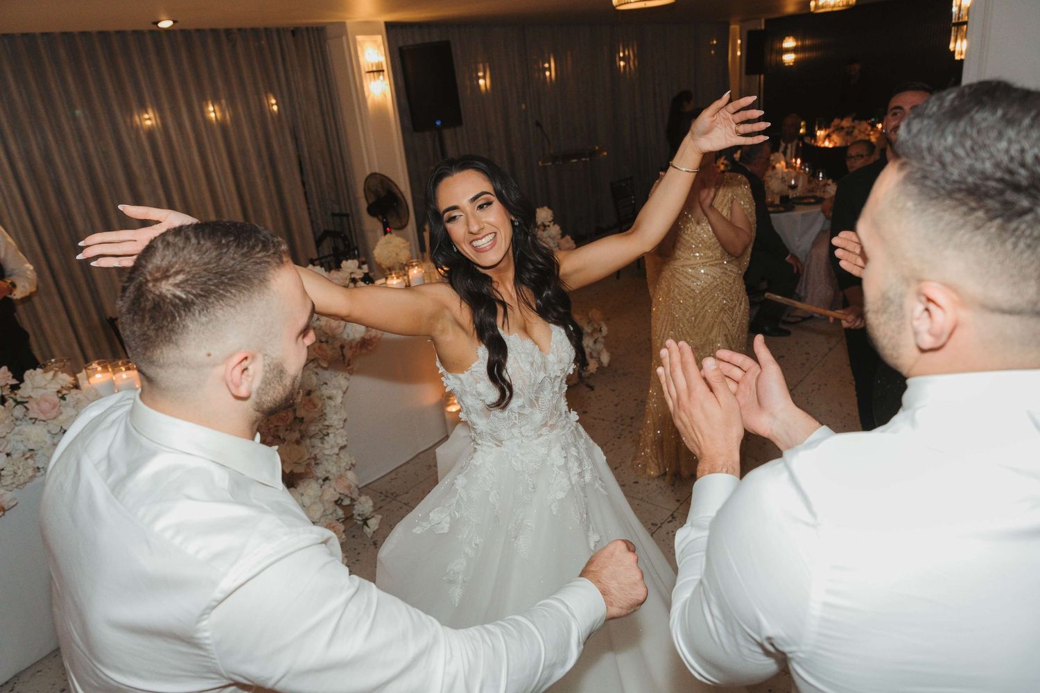 A sequence of celebratory dancing moments captured at a party with people in white outfits.