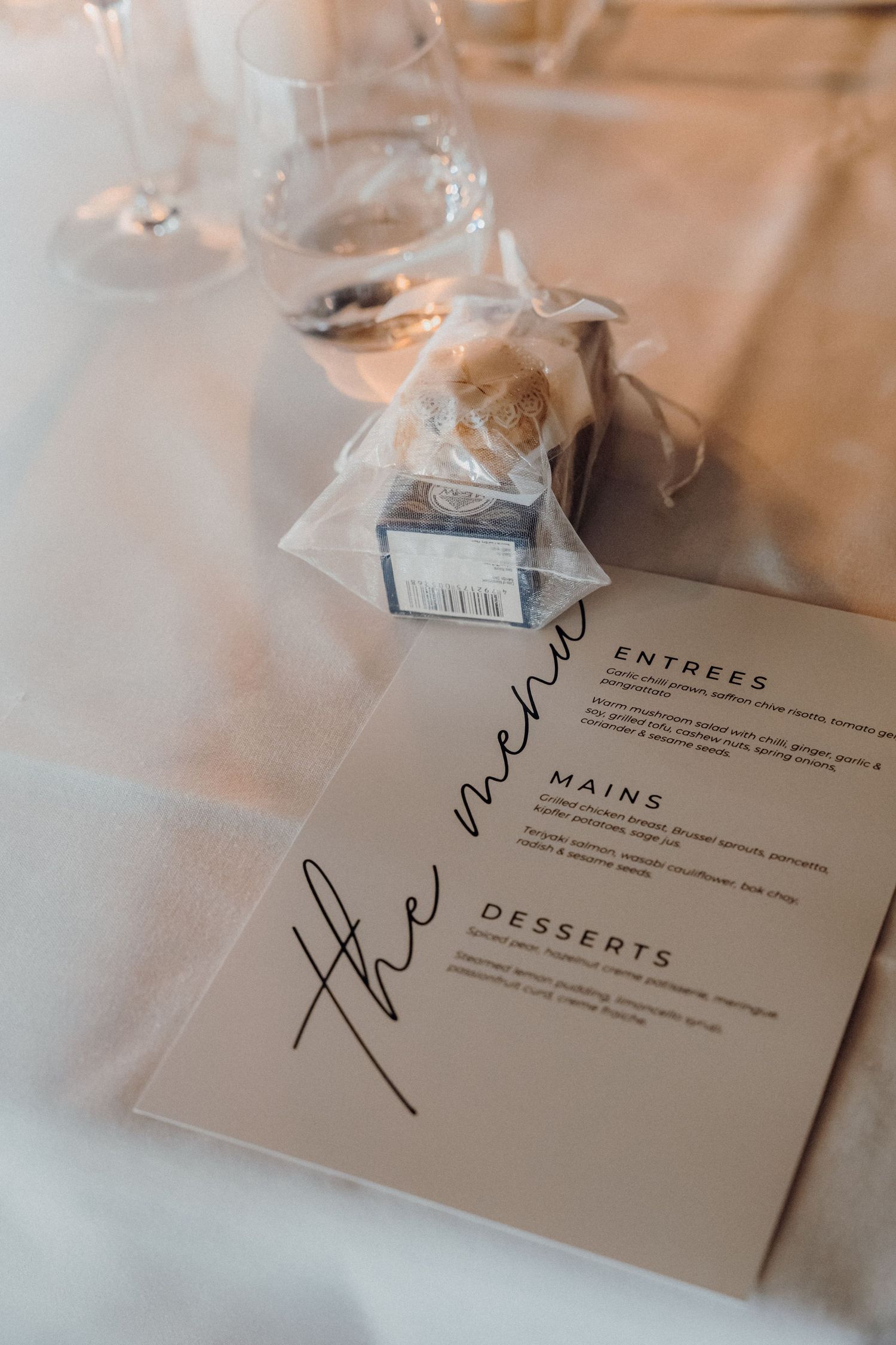 Elegant calligraphy written menu cards for desserts and mains courses displayed on a blurred table setting.