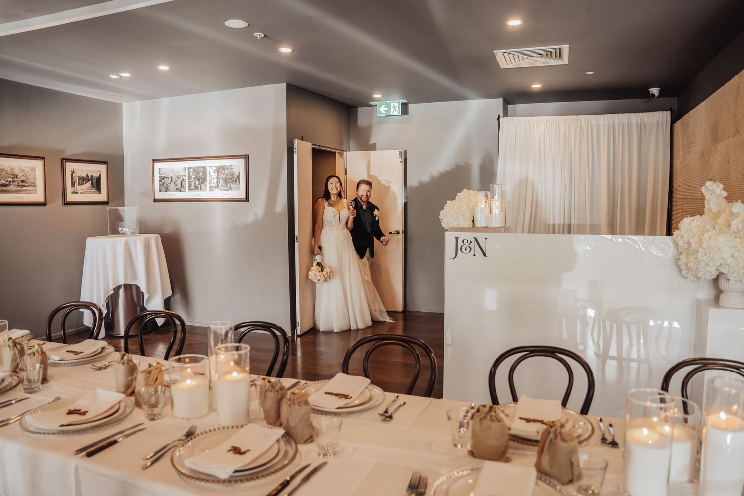 Elegant wedding reception table setting with white linens and candles in a modern restaurant private dining room.
