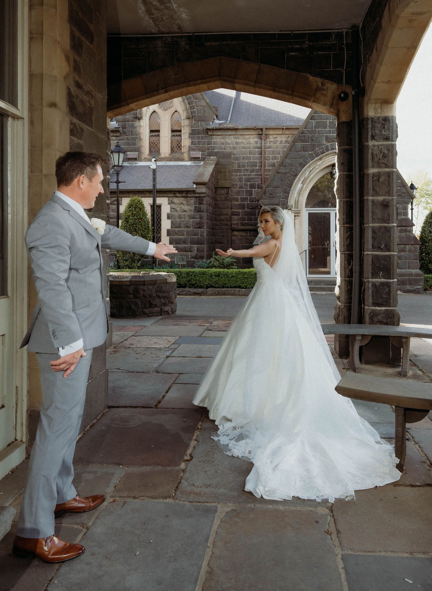 A couple shares their first look moment in a stone courtyard during their wedding celebration.