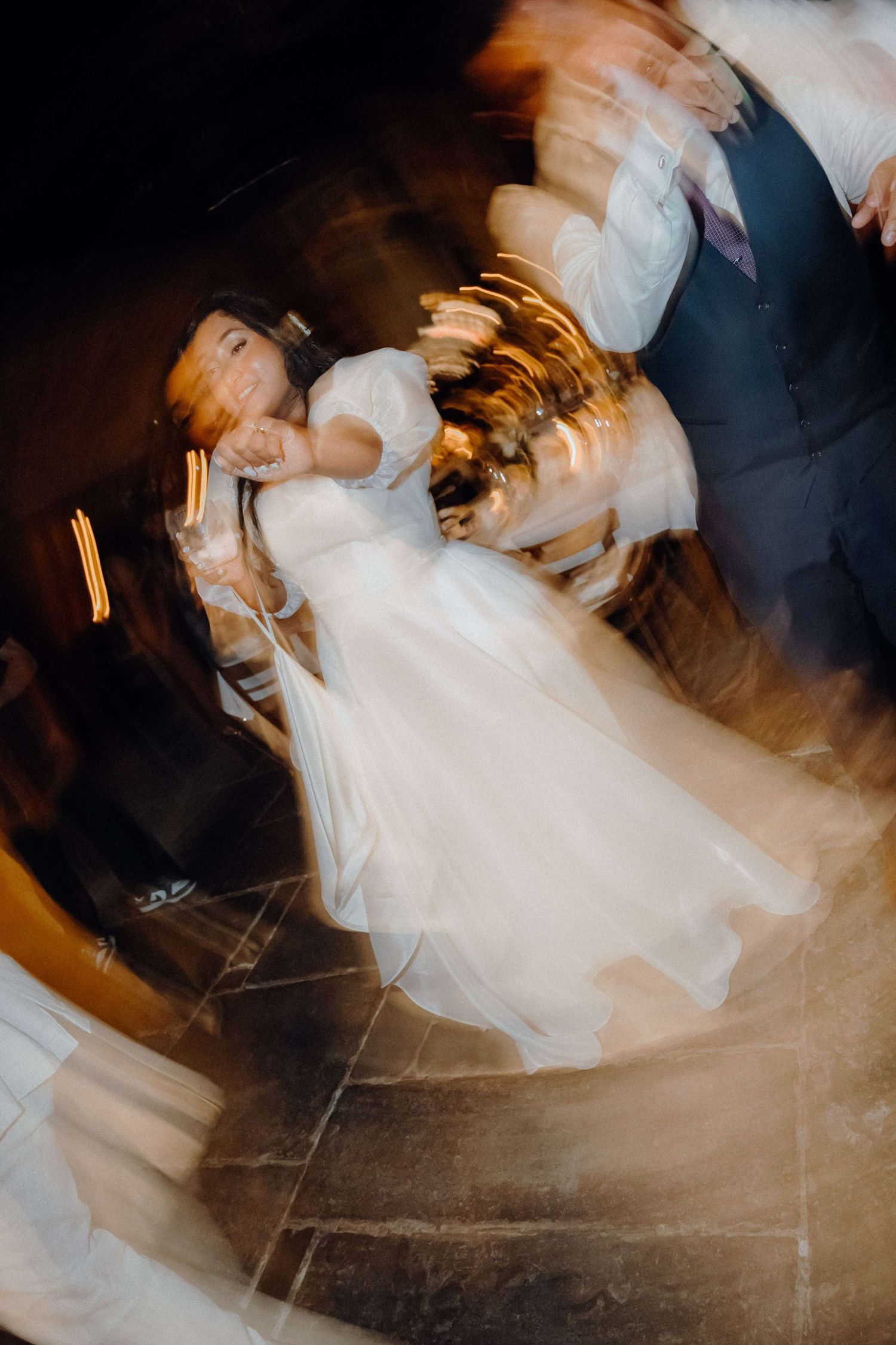Motion-blurred artistic dance photo showing swirling white dress and dramatic movement on dark background.