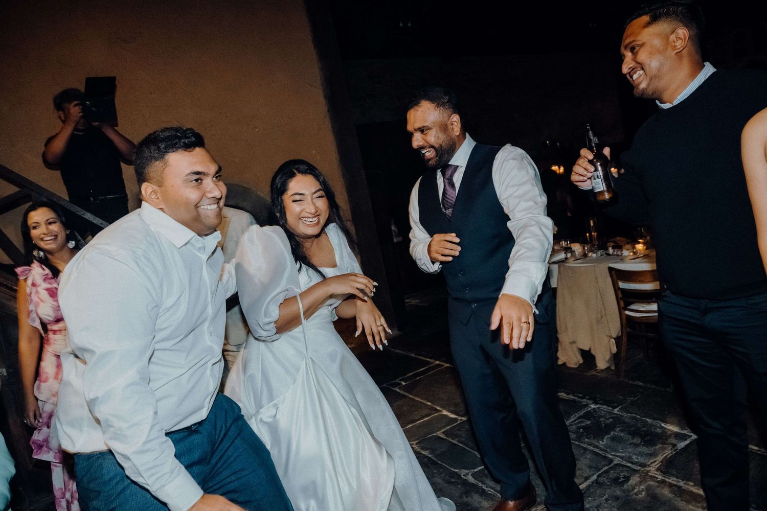 People celebrating and dancing together during a festive occasion, laughing and having fun on the dance floor.