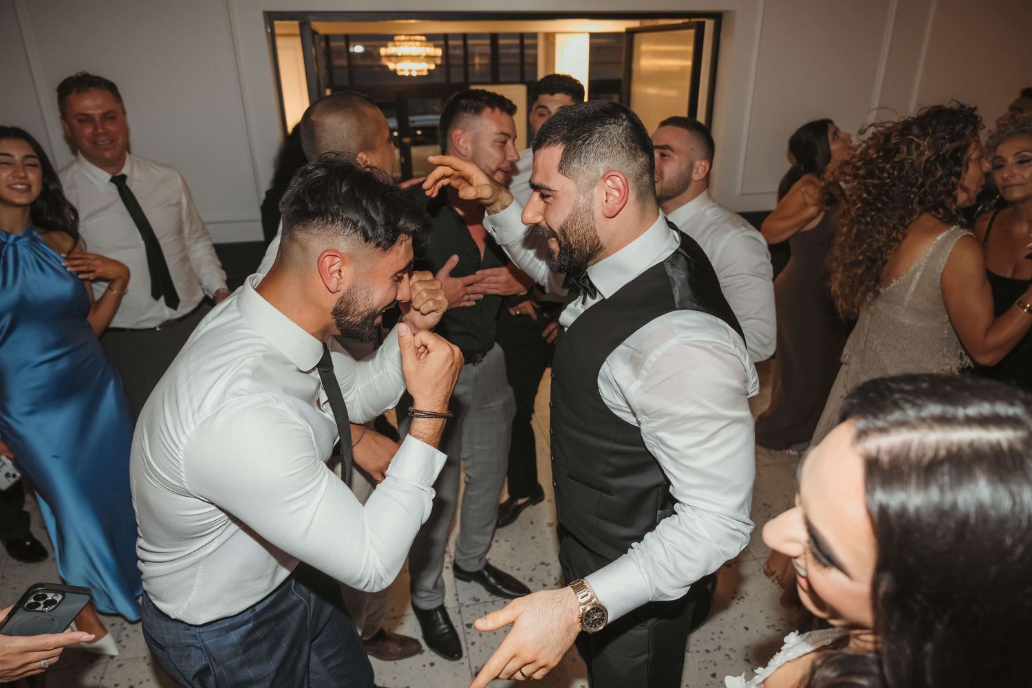Wedding guests dancing and celebrating together at an indoor reception party.