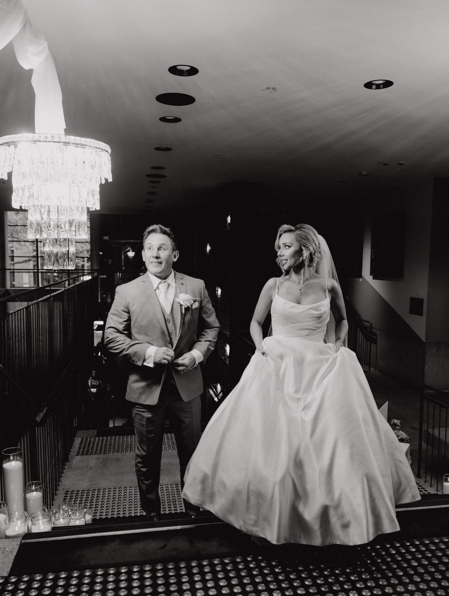 Black and white wedding photos showing a couple dancing and celebrating at an elegant reception with chandeliers.