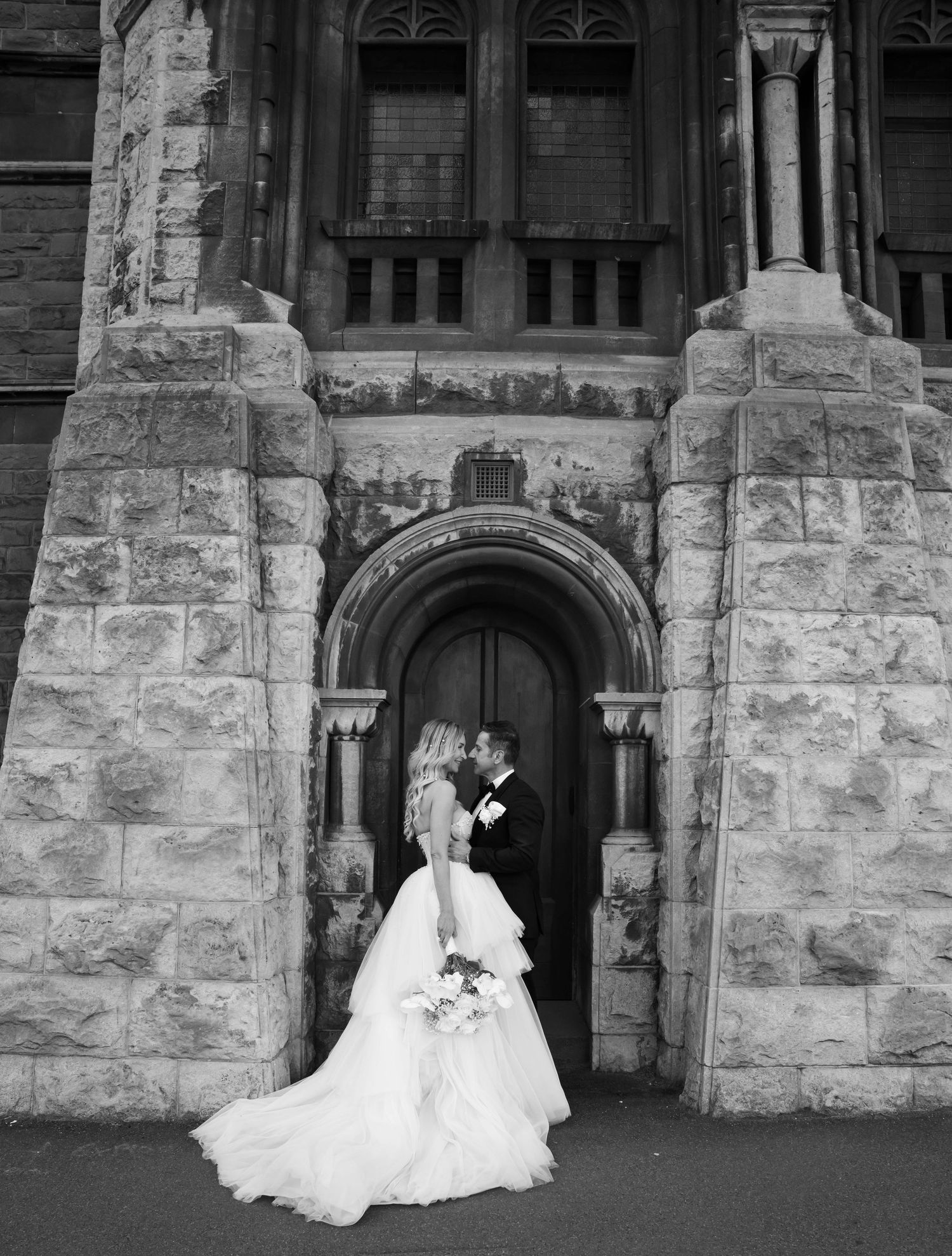 A series of black and white wedding photos showing a couple in front of a stone church entrance with elegant archways.