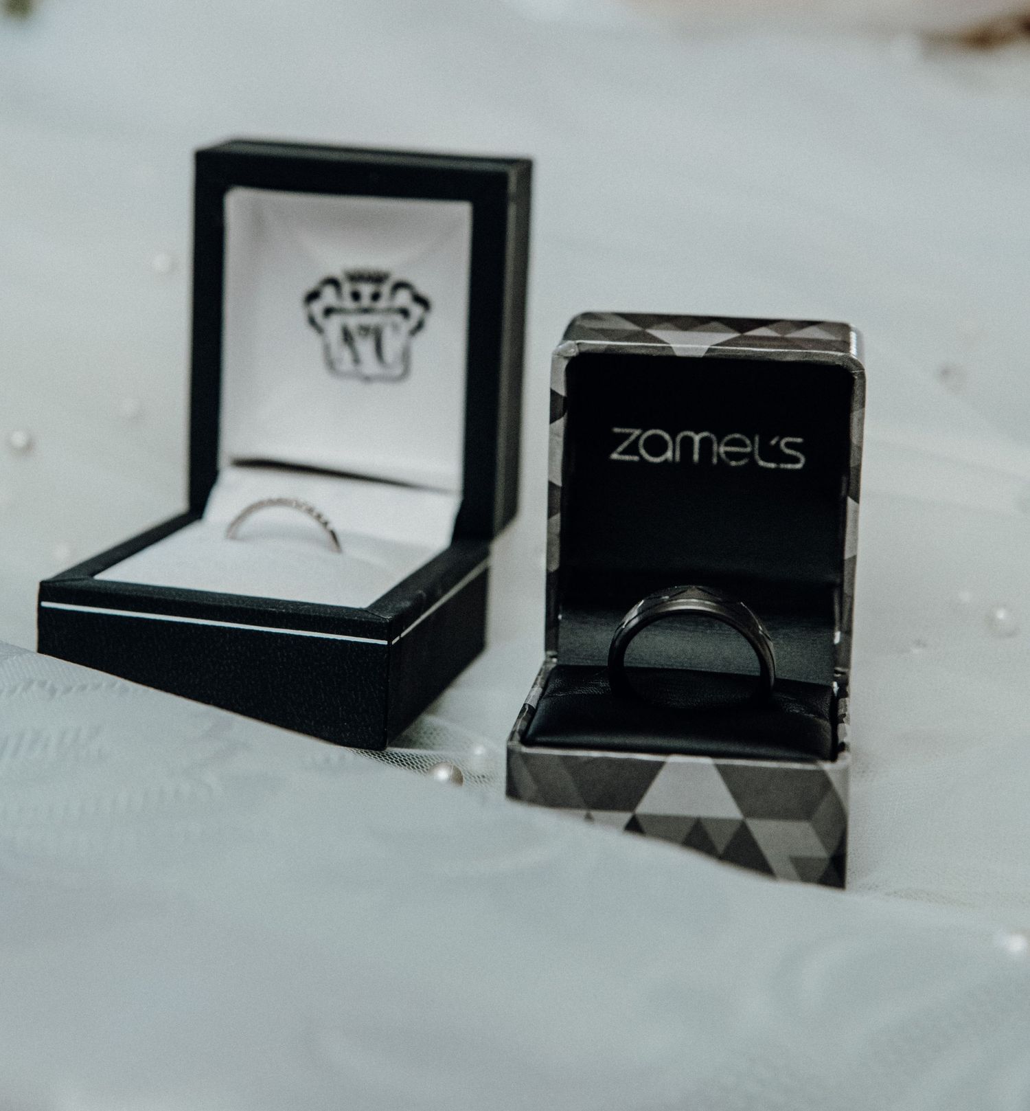 Multiple open black jewelry boxes arranged in a row displaying various rings and accessories against a light surface.