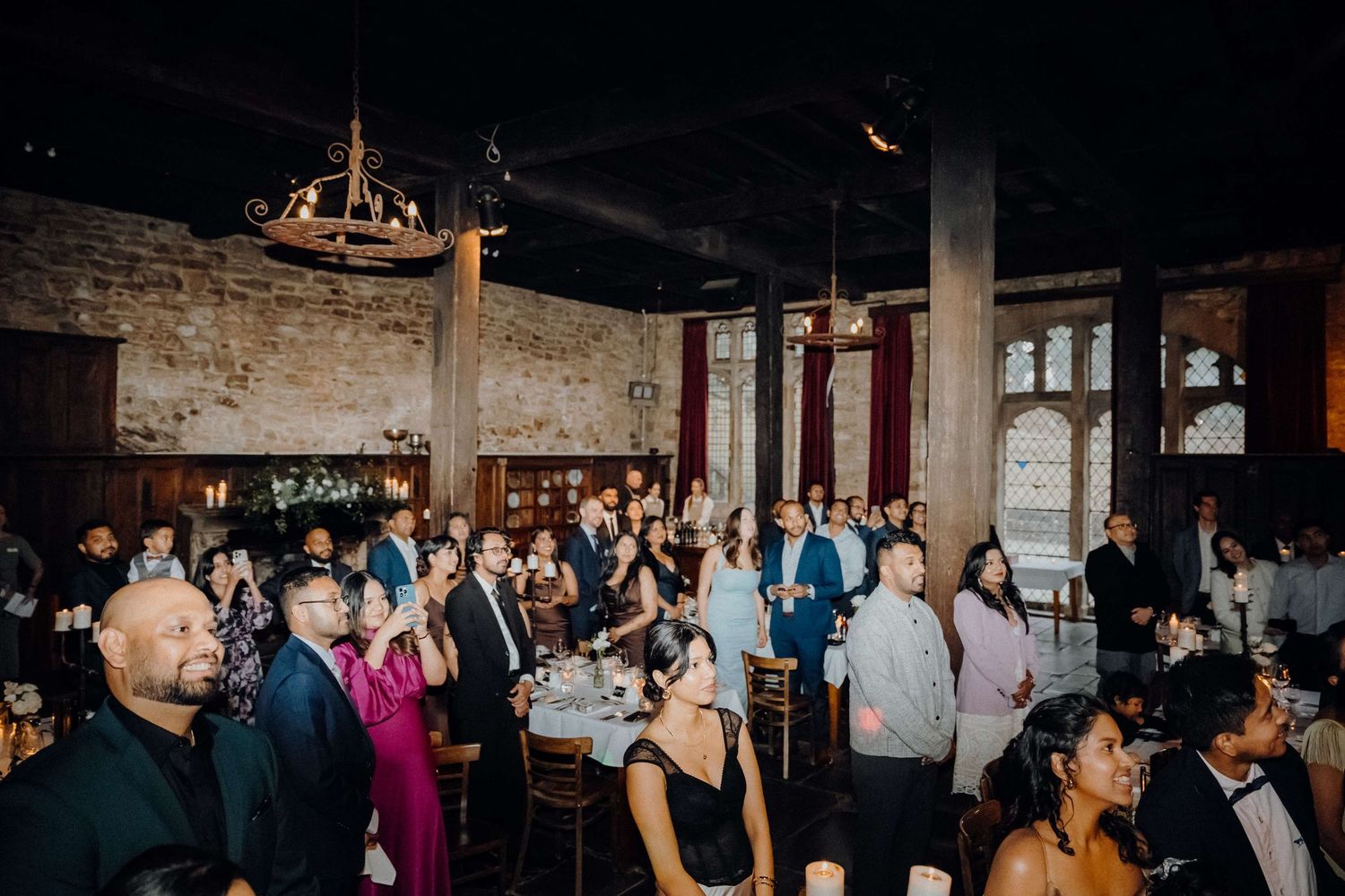 Wedding reception guests dancing and celebrating in an industrial-chic venue with exposed brick walls and chandeliers.