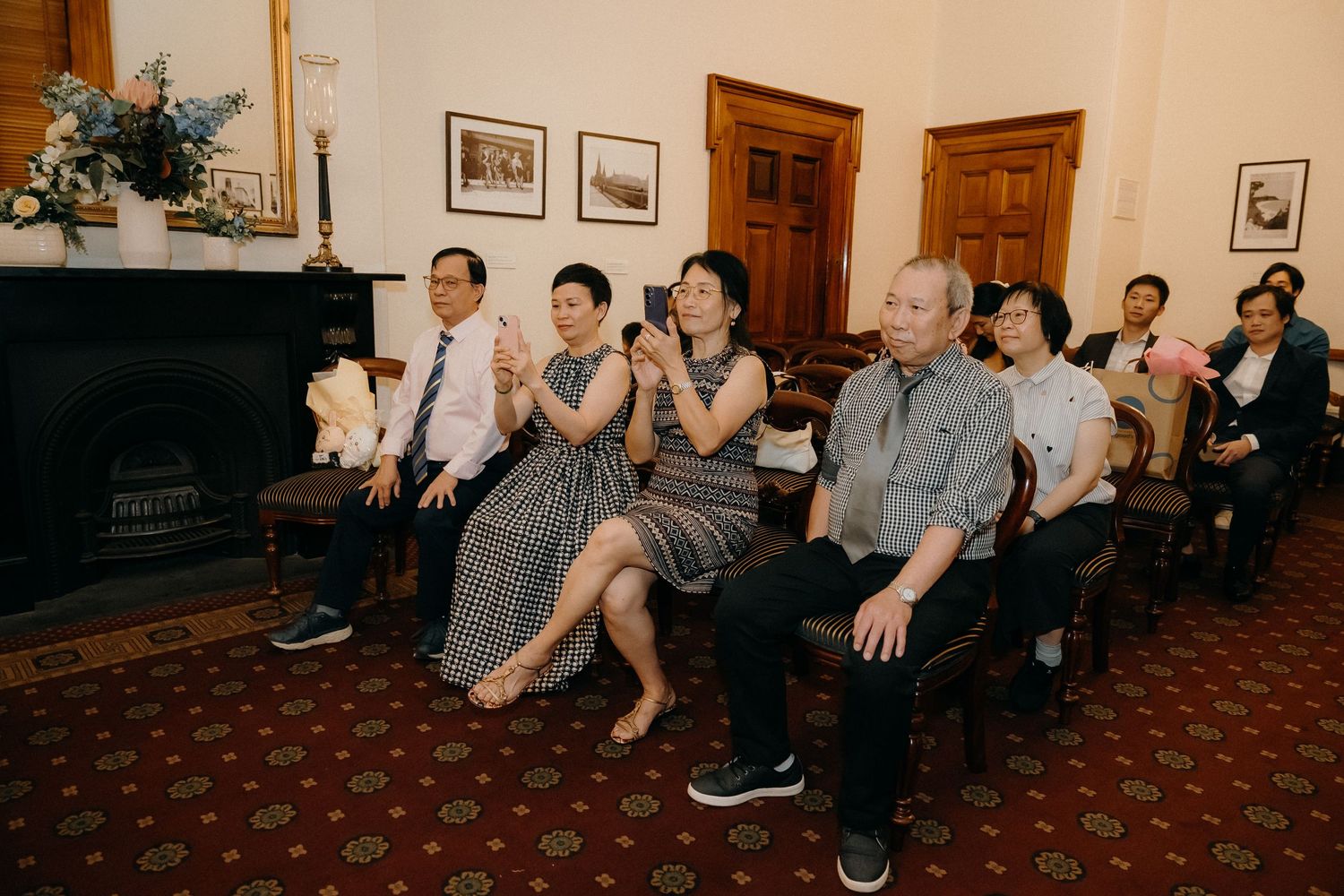 A sequence of dance class participants sitting and stretching in a line on a carpeted floor.