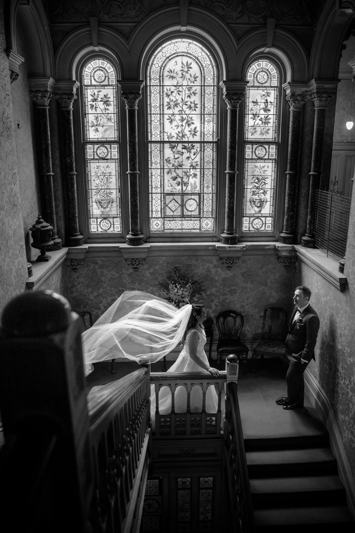 A haunting black and white photo shows hospital beds in a room with ornate arched stained glass windows.
