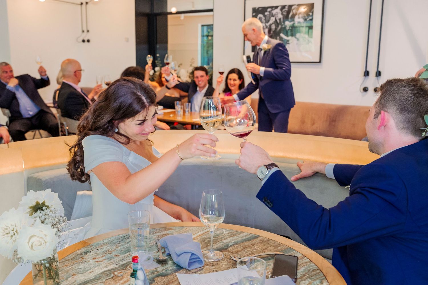 People gathered around a long table for a wine tasting event in a modern, bright venue.
