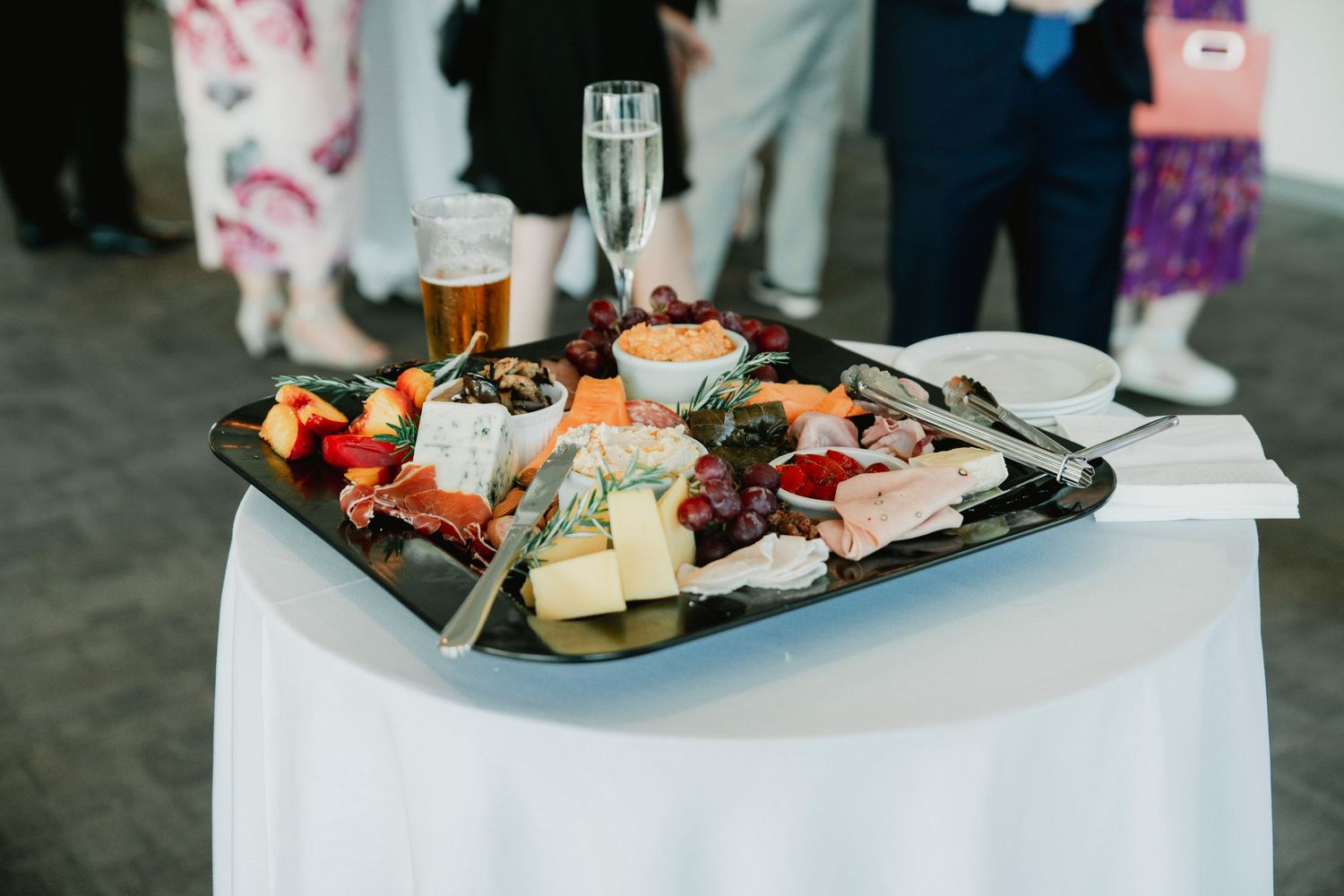 Assorted appetizer plates with cheese, meats, and garnishes arranged on a white tablecloth at an event.