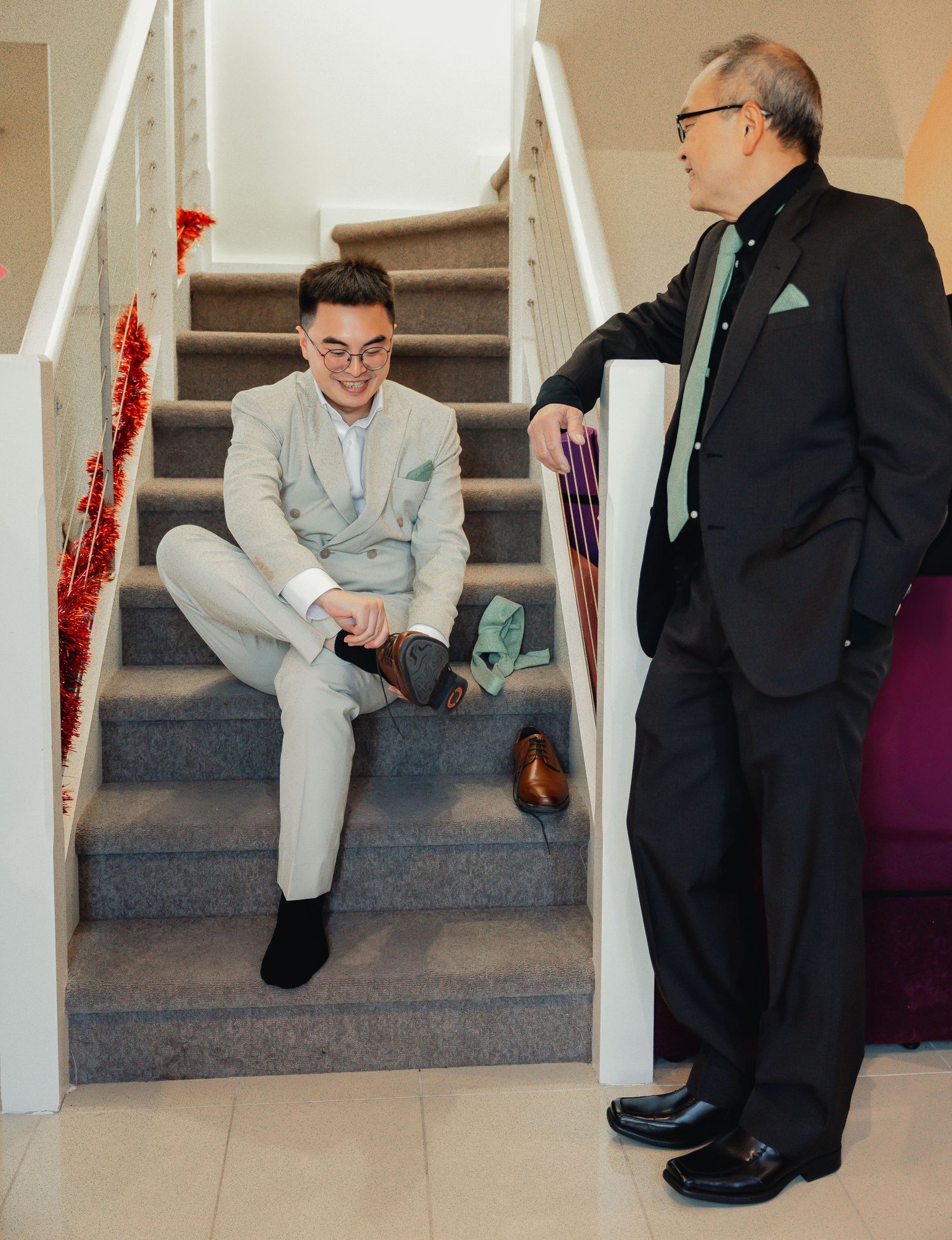 Two people in contrasting suits sit having a discussion on modern white stairs in an interior space.