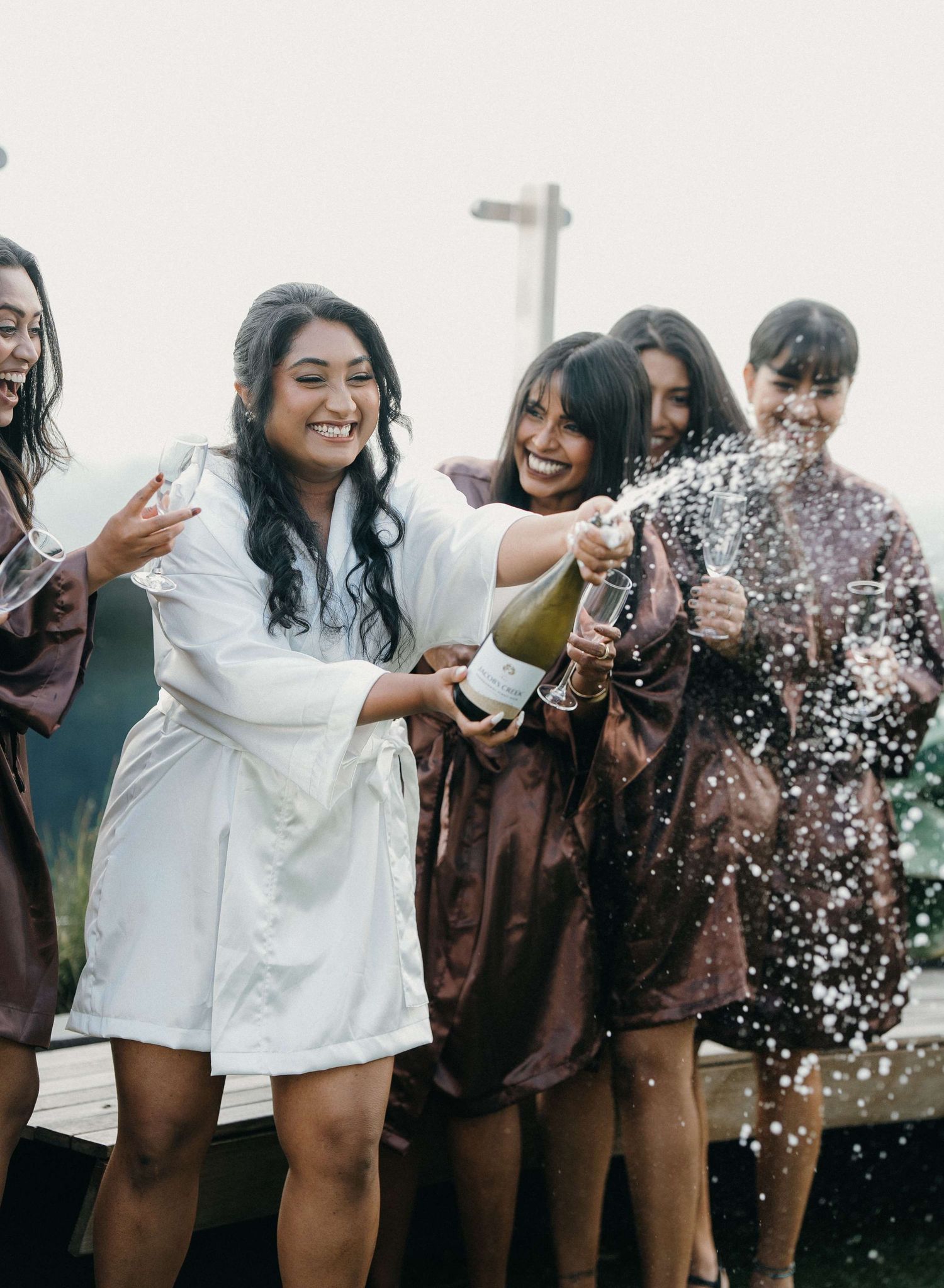 A group of friends having fun tossing confetti and glitter in the air while celebrating outdoors in casual attire.