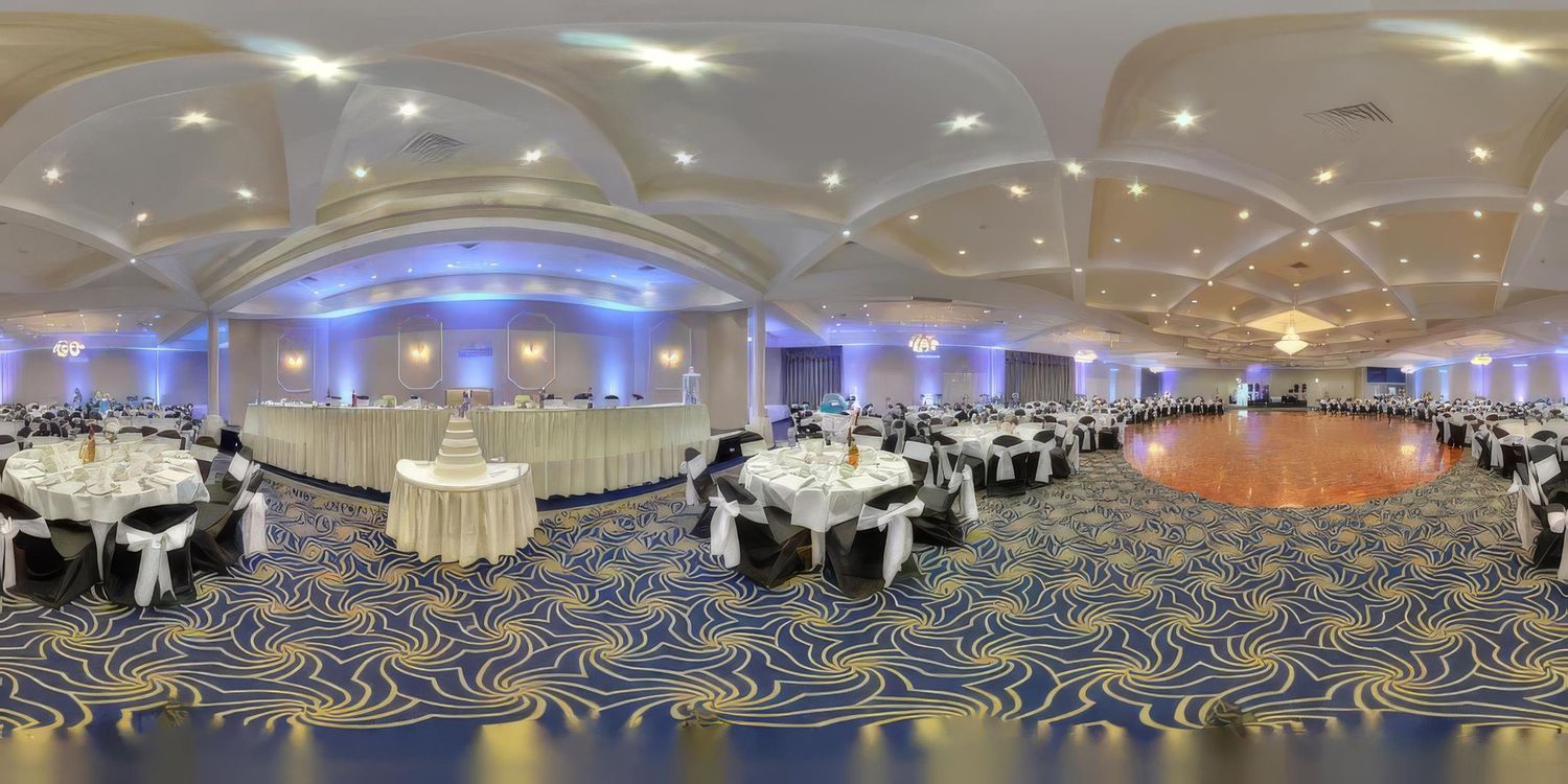 A panoramic view of a large empty ballroom with modern lighting and geometric ceiling patterns.
