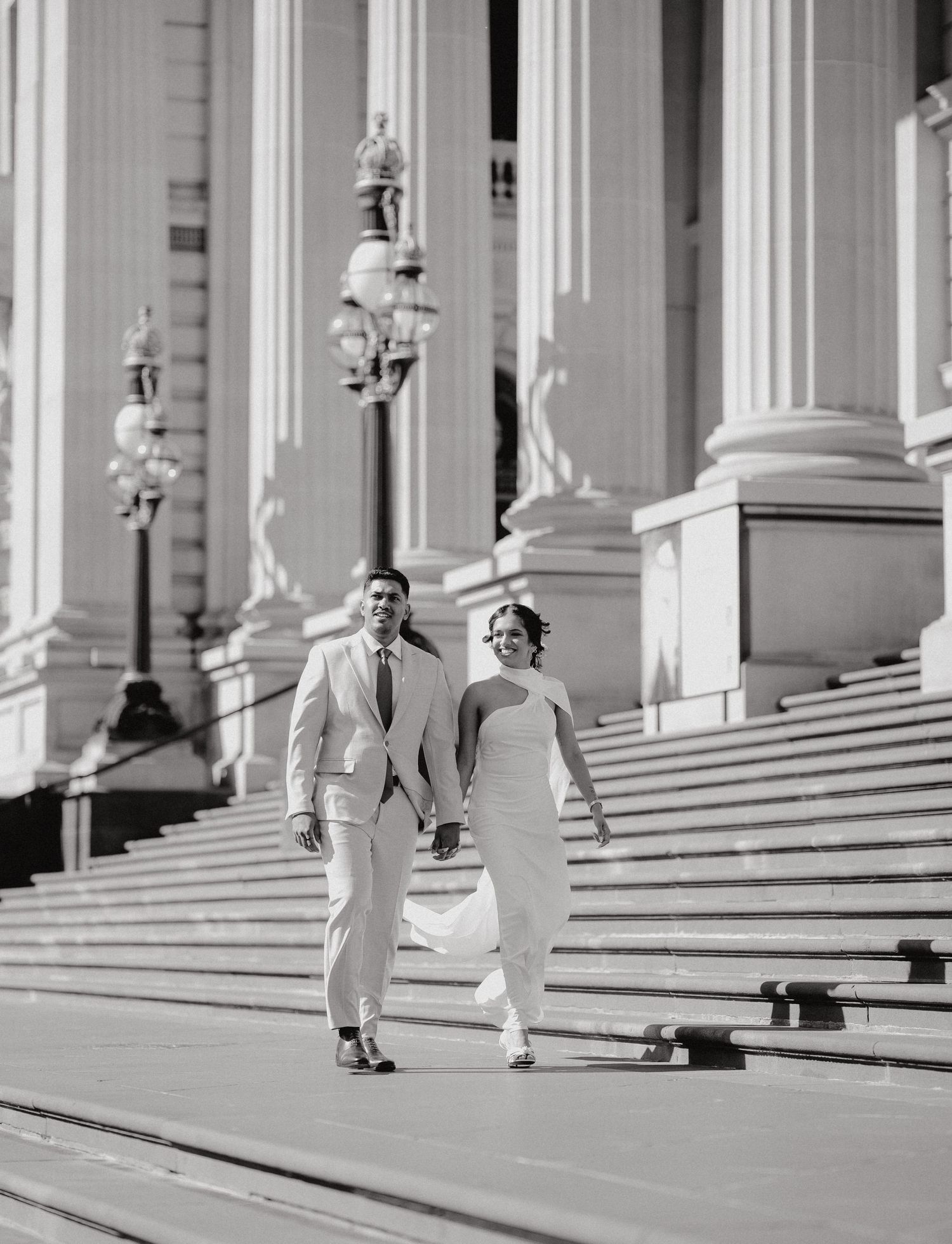 A black and white panoramic sequence showing a person walking up white marble steps between classical columns.