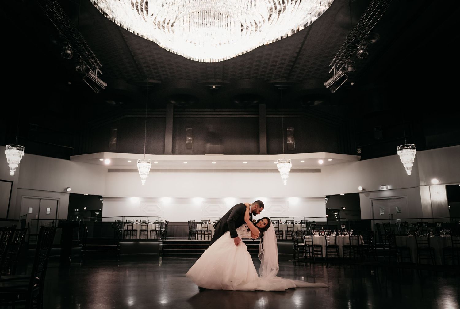 A dramatic ballroom wedding scene with elegant lighting and a romantic dance dip on an empty dance floor.