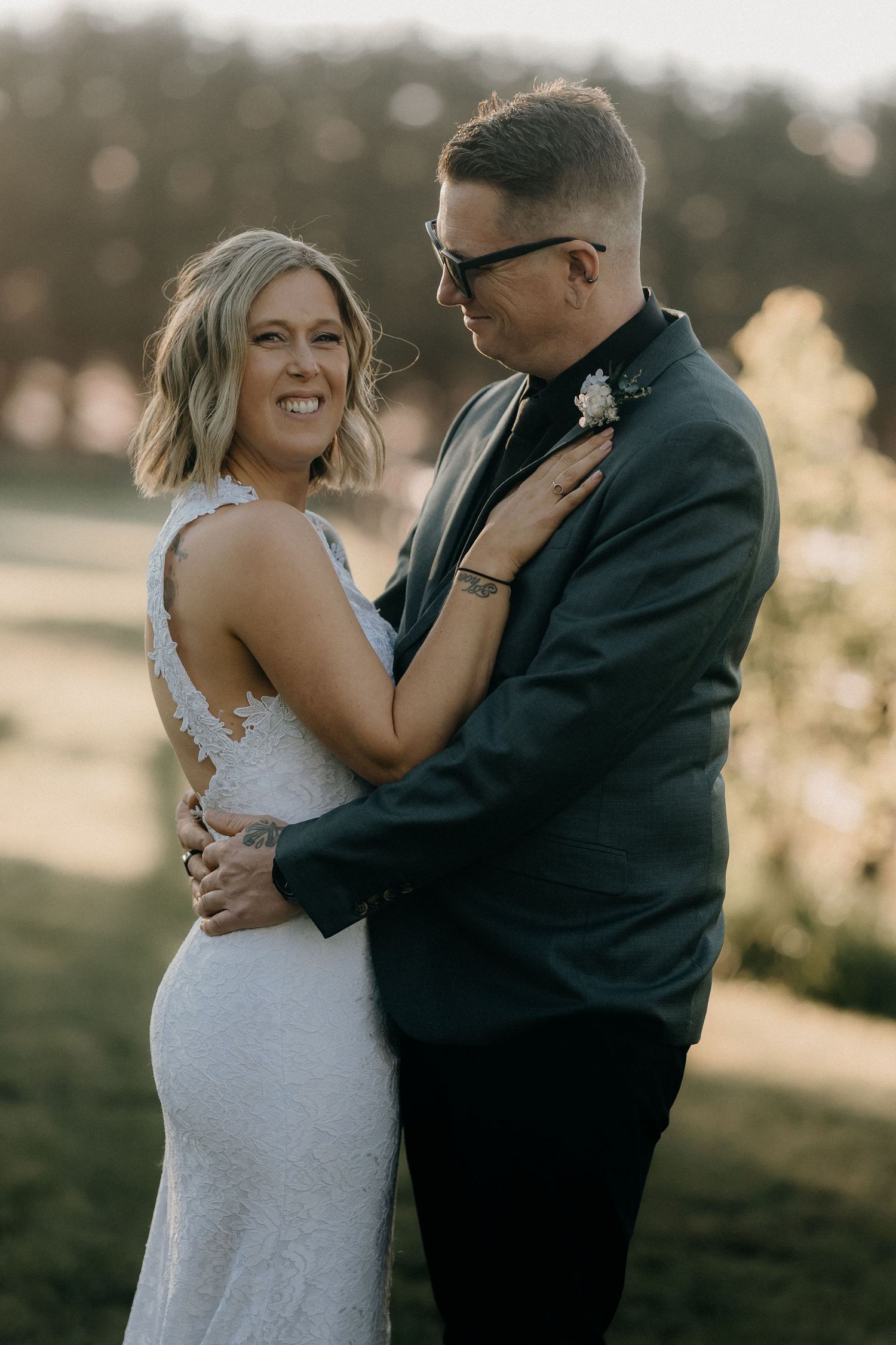 A romantic couple embraces outdoors during a sunset wedding photoshoot in a park setting.