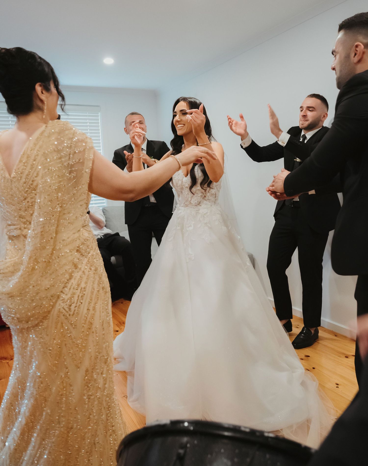 Wedding party dancing and celebrating together in white room with wooden floors and joyful atmosphere.