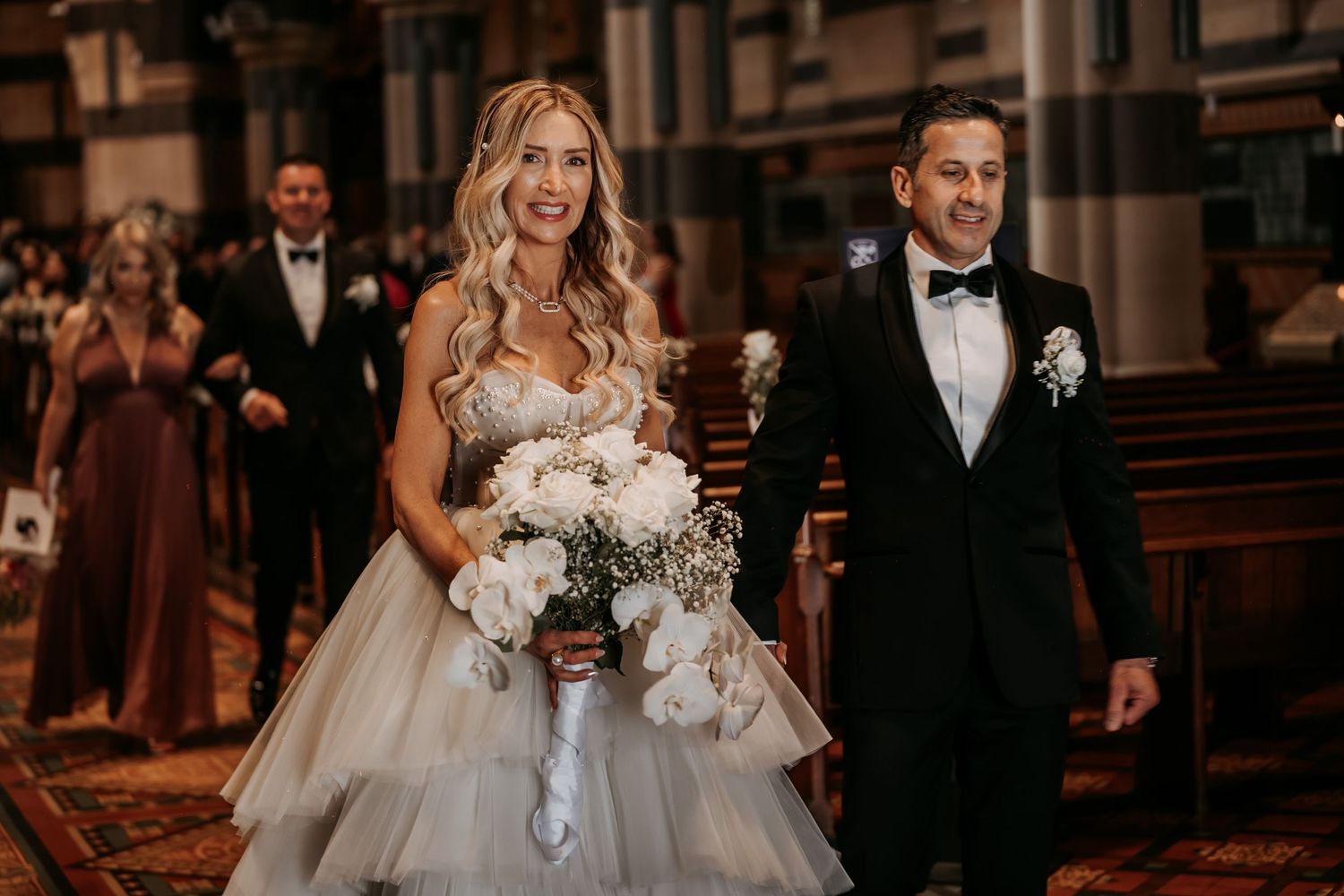A wedding ceremony in a grand cathedral with elegant floral arrangements and formal attire.